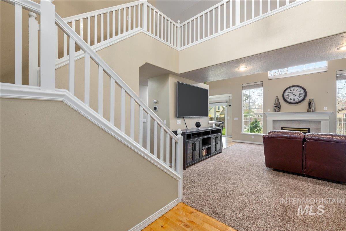 Living area featuring a tiled fireplace, light wood-type flooring, and a high ceiling