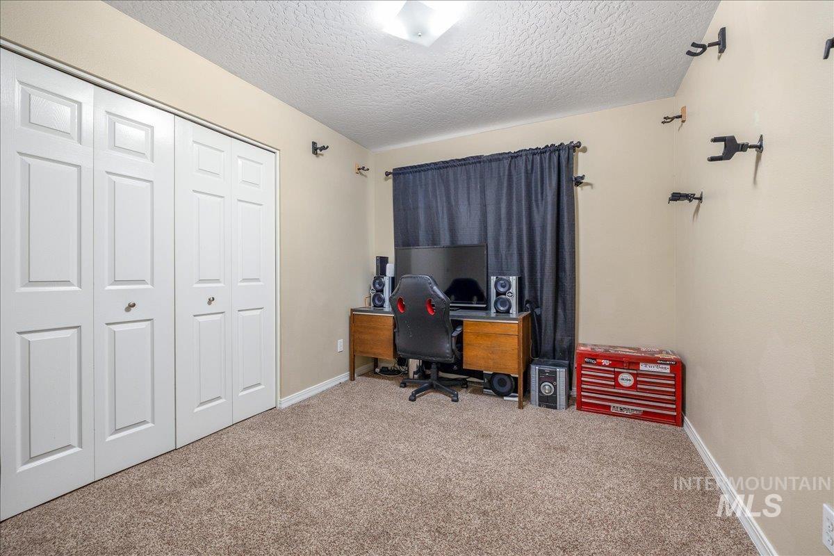 Carpeted office space featuring a textured ceiling and baseboards