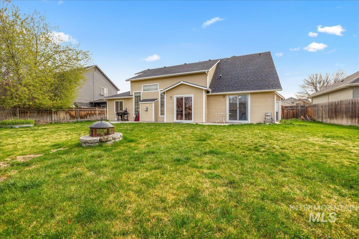 Back of house with a fire pit, a fenced backyard, a patio area, and roof with shingles