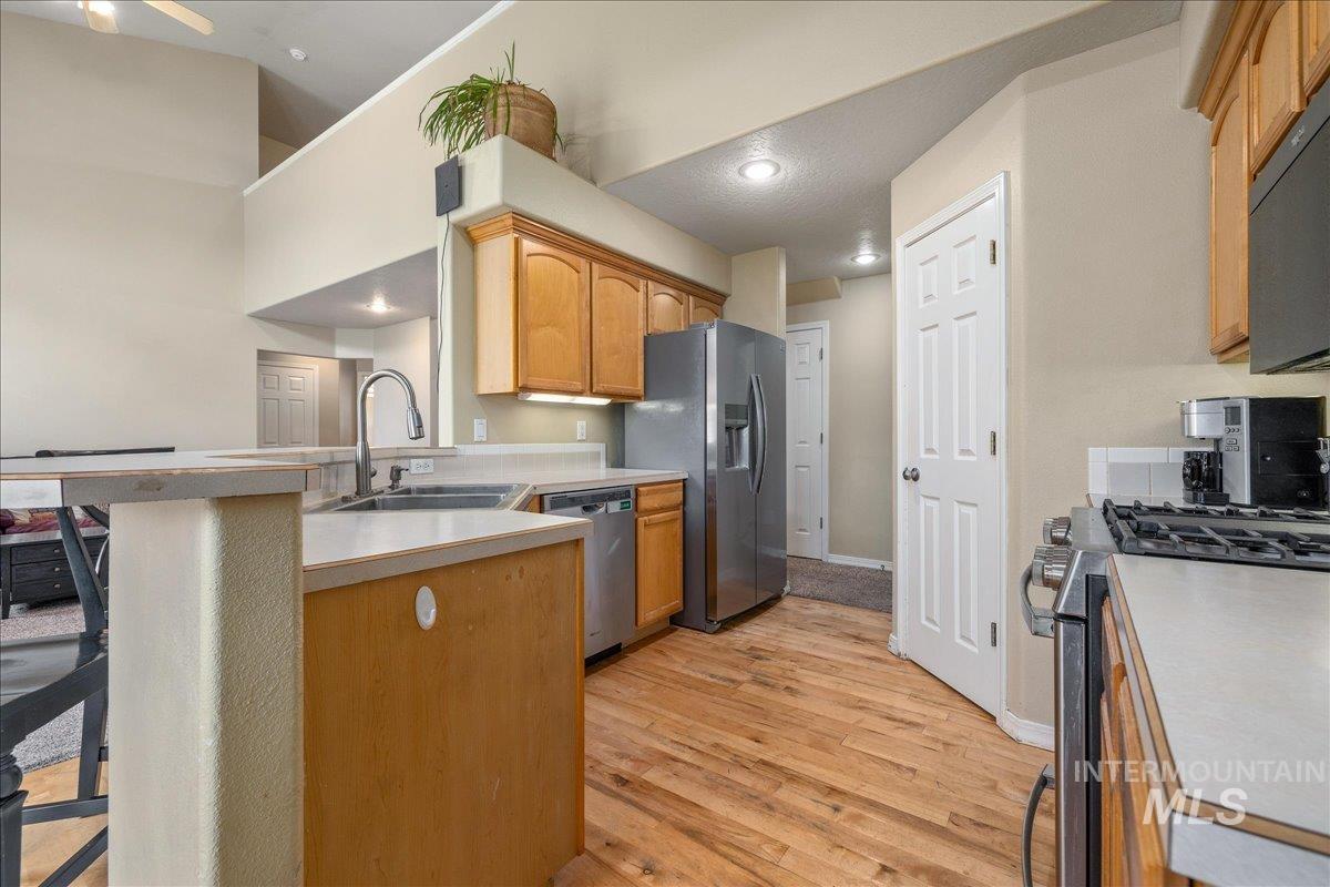 Kitchen featuring a peninsula, stainless steel appliances, light countertops, light wood-type flooring, and a breakfast bar