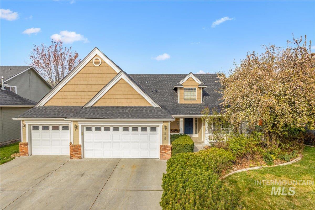 Traditional home featuring concrete driveway, a garage, brick siding, and a shingled roof