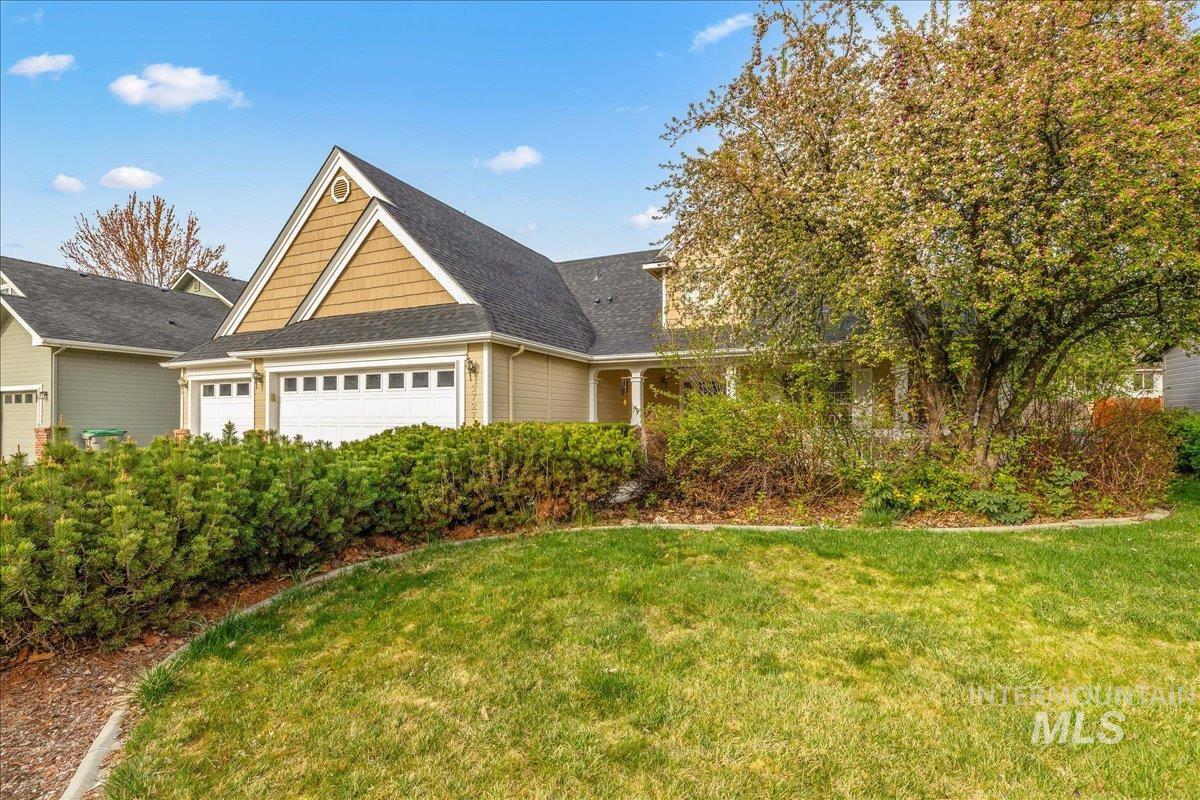 View of front of home featuring a front yard, a shingled roof, and an attached garage