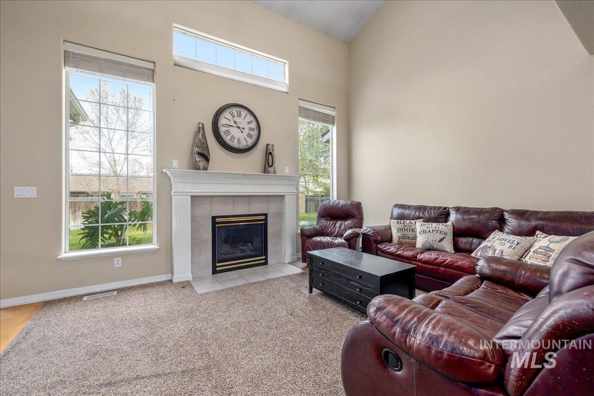 Living area with a tile fireplace, light carpet, and a high ceiling