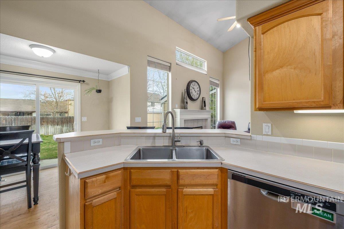 Kitchen with light countertops, dishwasher, a peninsula, wood finish cabinets, and light wood-style floors