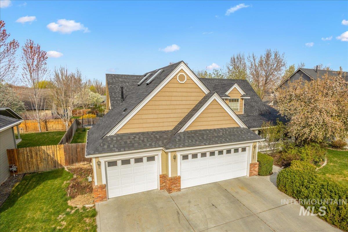 Traditional-style home featuring a shingled roof, concrete driveway, brick siding, and a garage