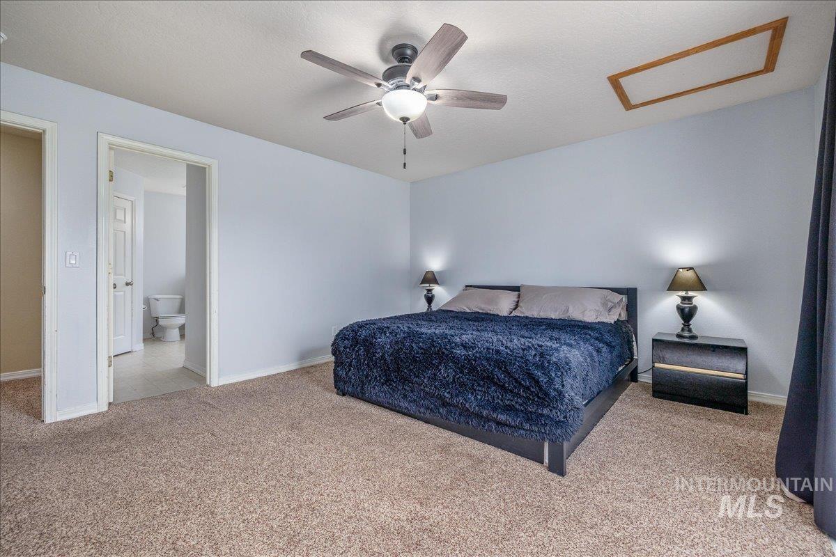Bedroom with light colored carpet, a ceiling fan, and ensuite bath