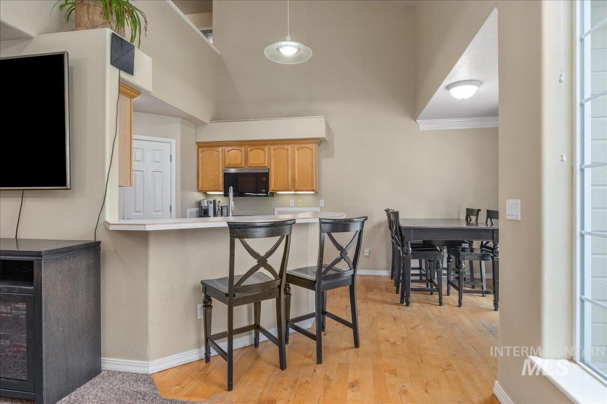 Kitchen featuring light countertops, a breakfast bar, a peninsula, pendant lighting, and light wood finished floors