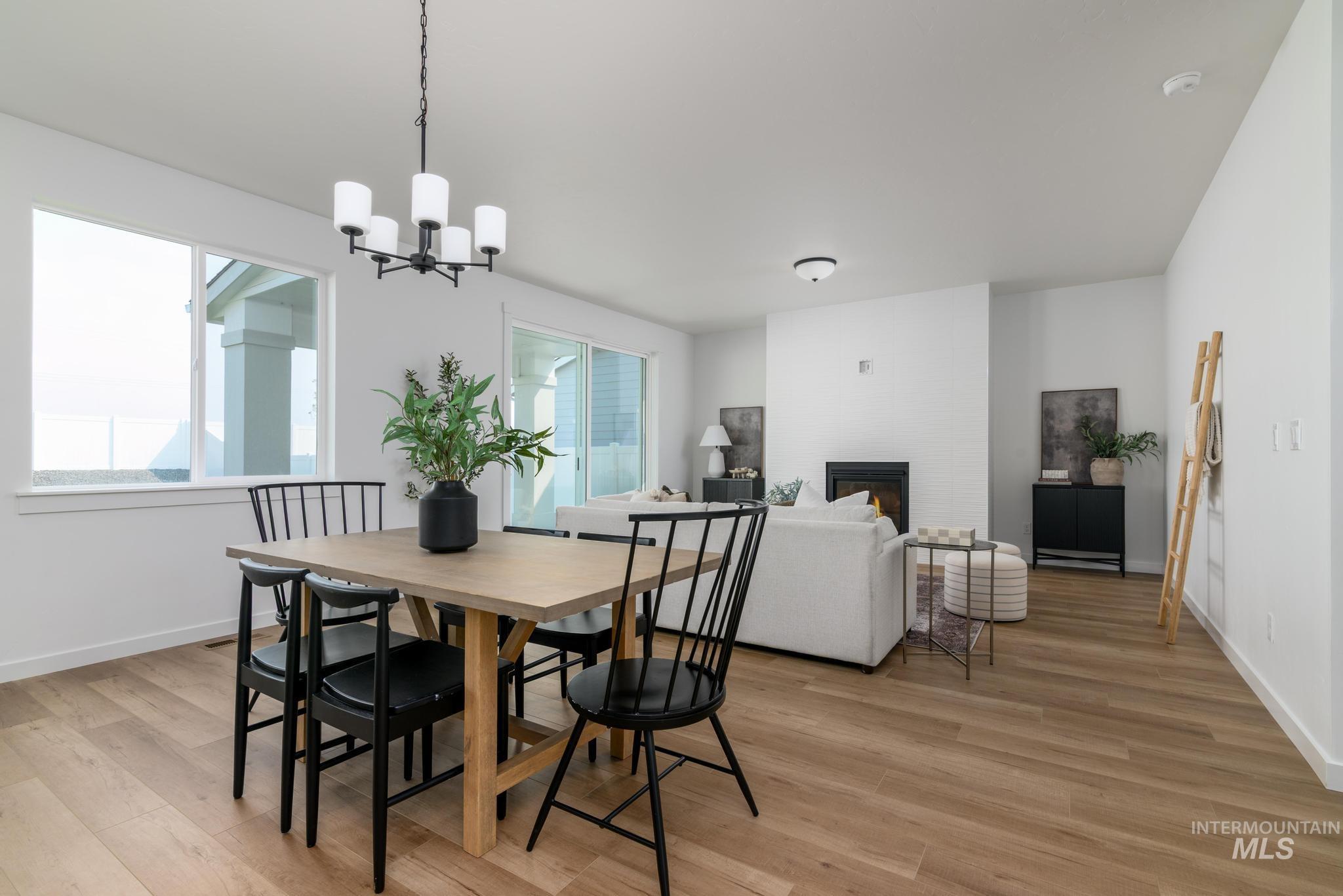 Dining space featuring a glass covered fireplace, light wood finished floors, and a chandelier