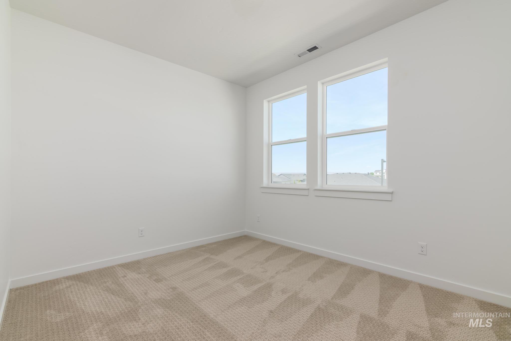 Empty room with light colored carpet and baseboards