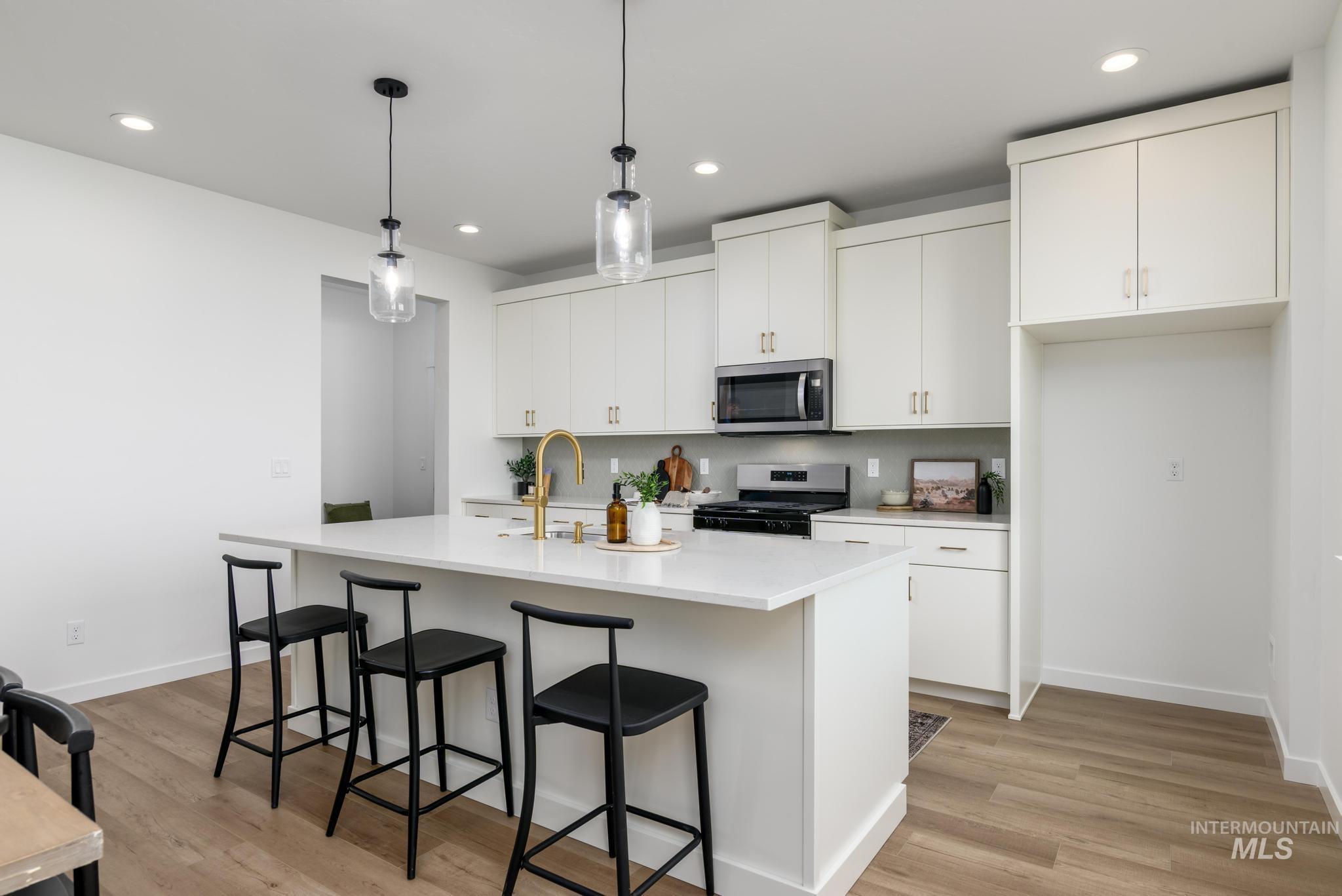 Kitchen with white cabinets, gas range, pendant lighting, stainless steel microwave, and recessed lighting