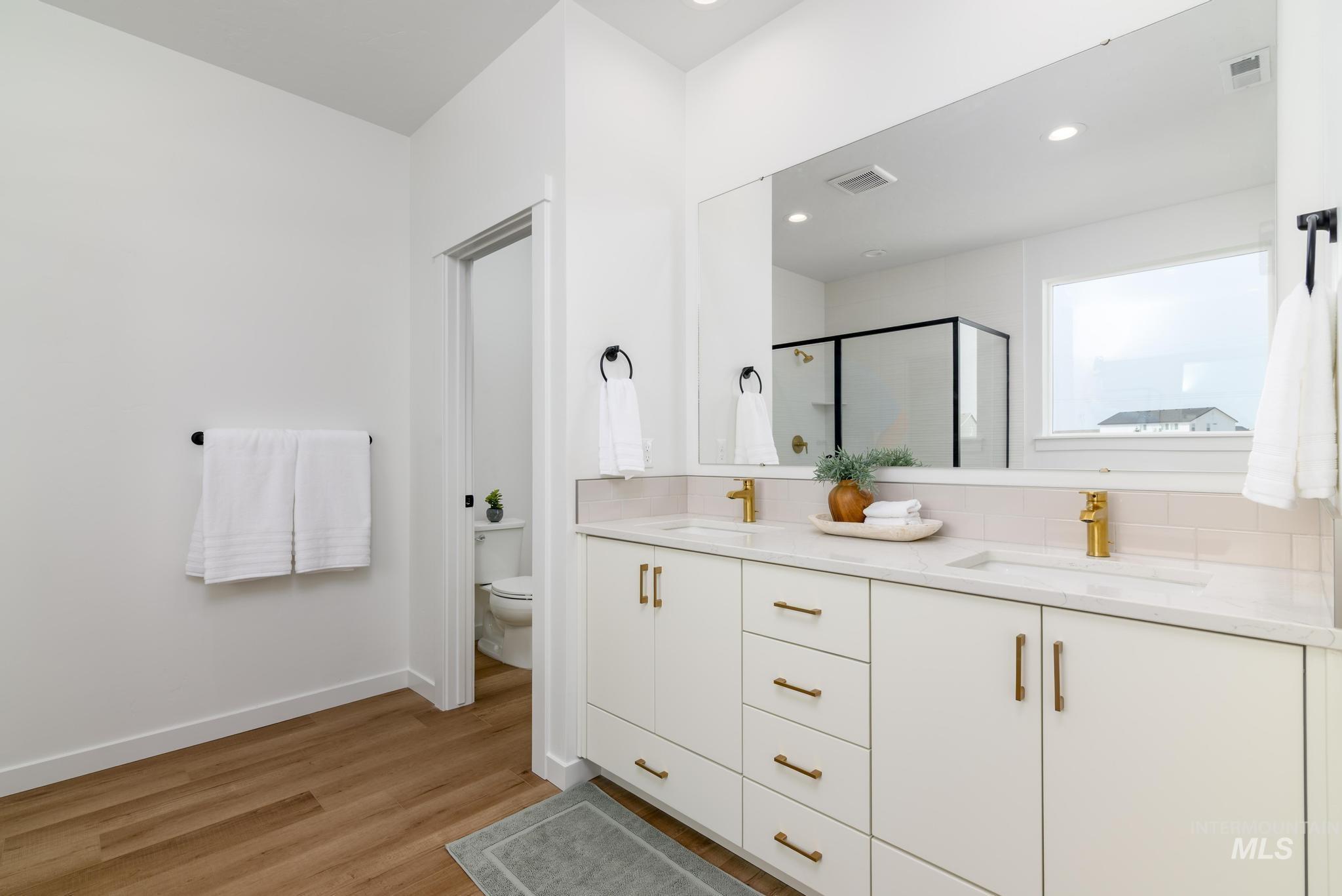 Bathroom with a shower stall, light wood-style flooring, double vanity, and recessed lighting