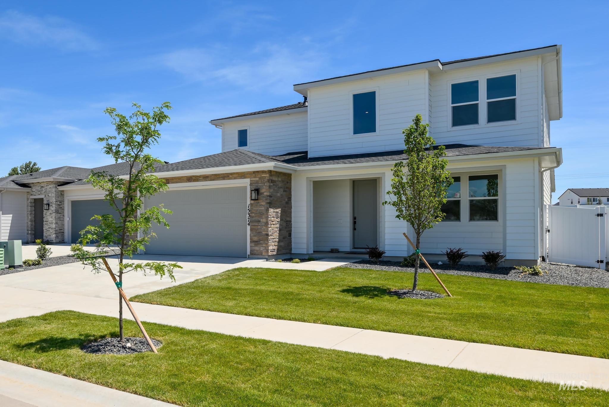 View of front of house featuring a garage, a front yard, driveway, and roof with shingles