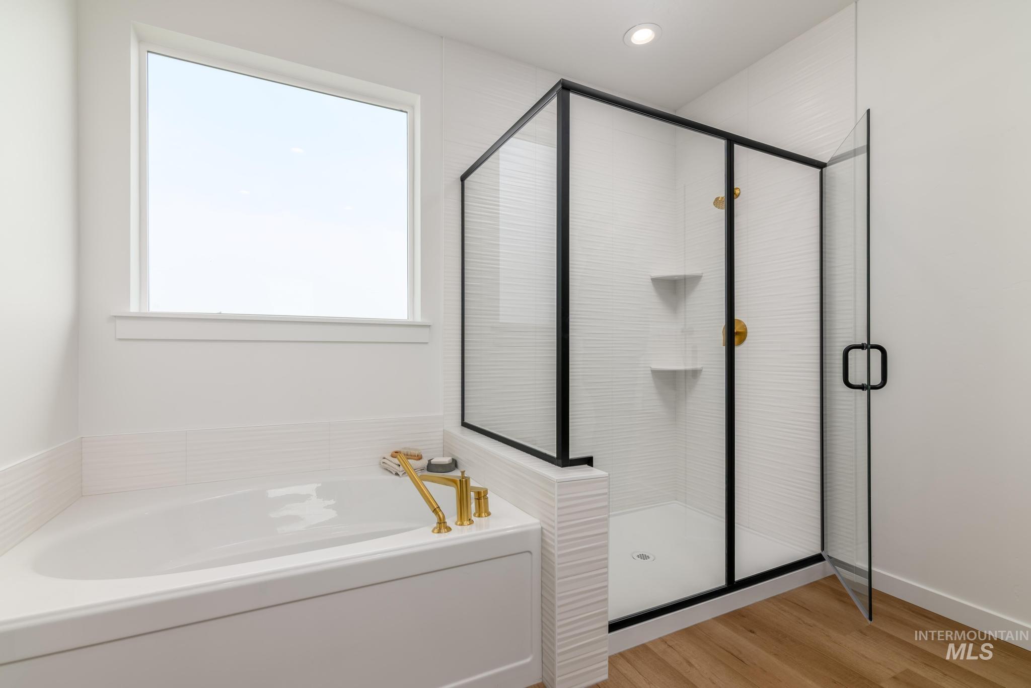 Full bath featuring a garden tub, a shower stall, and light wood-type flooring