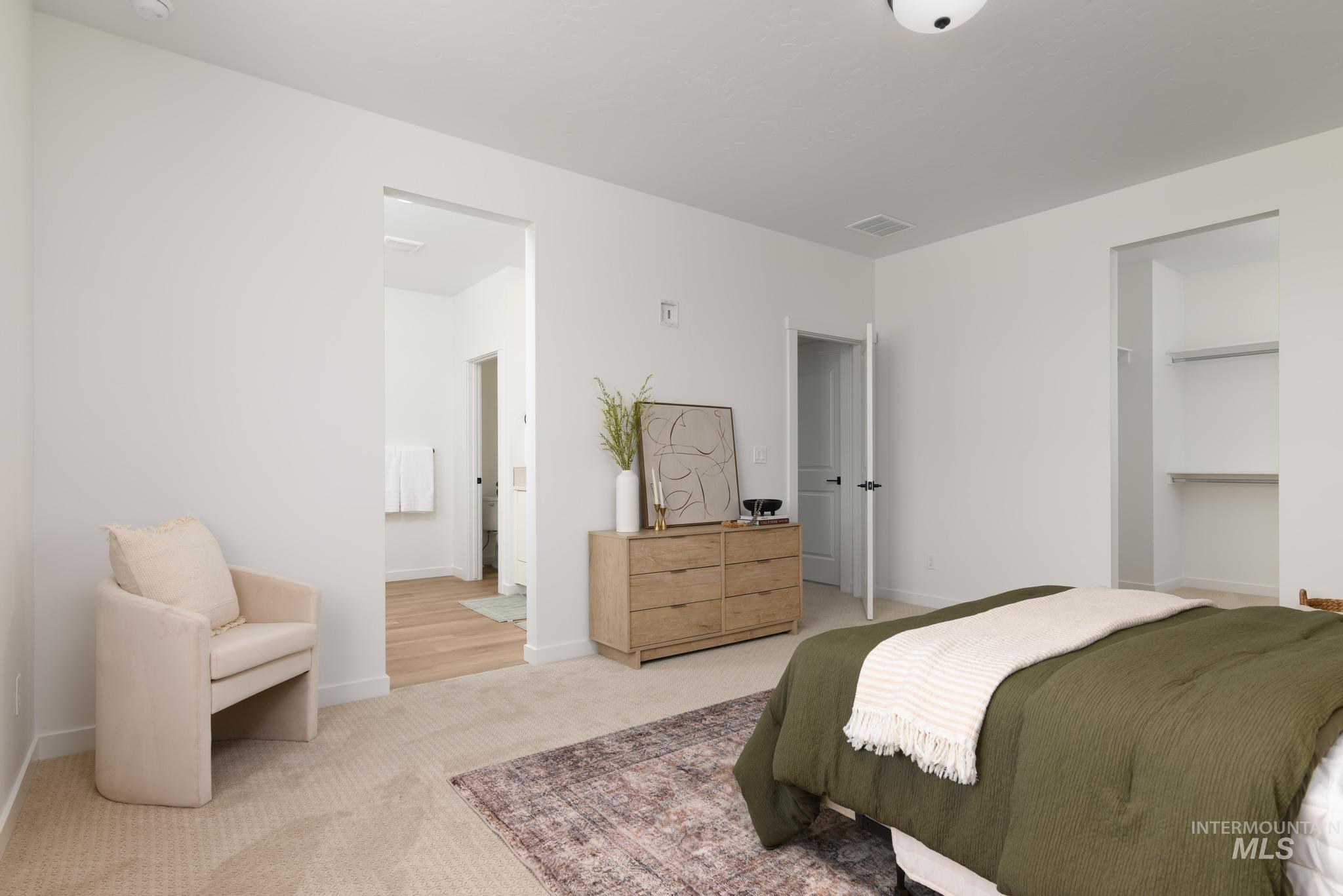 Carpeted bedroom featuring ensuite bathroom and baseboards