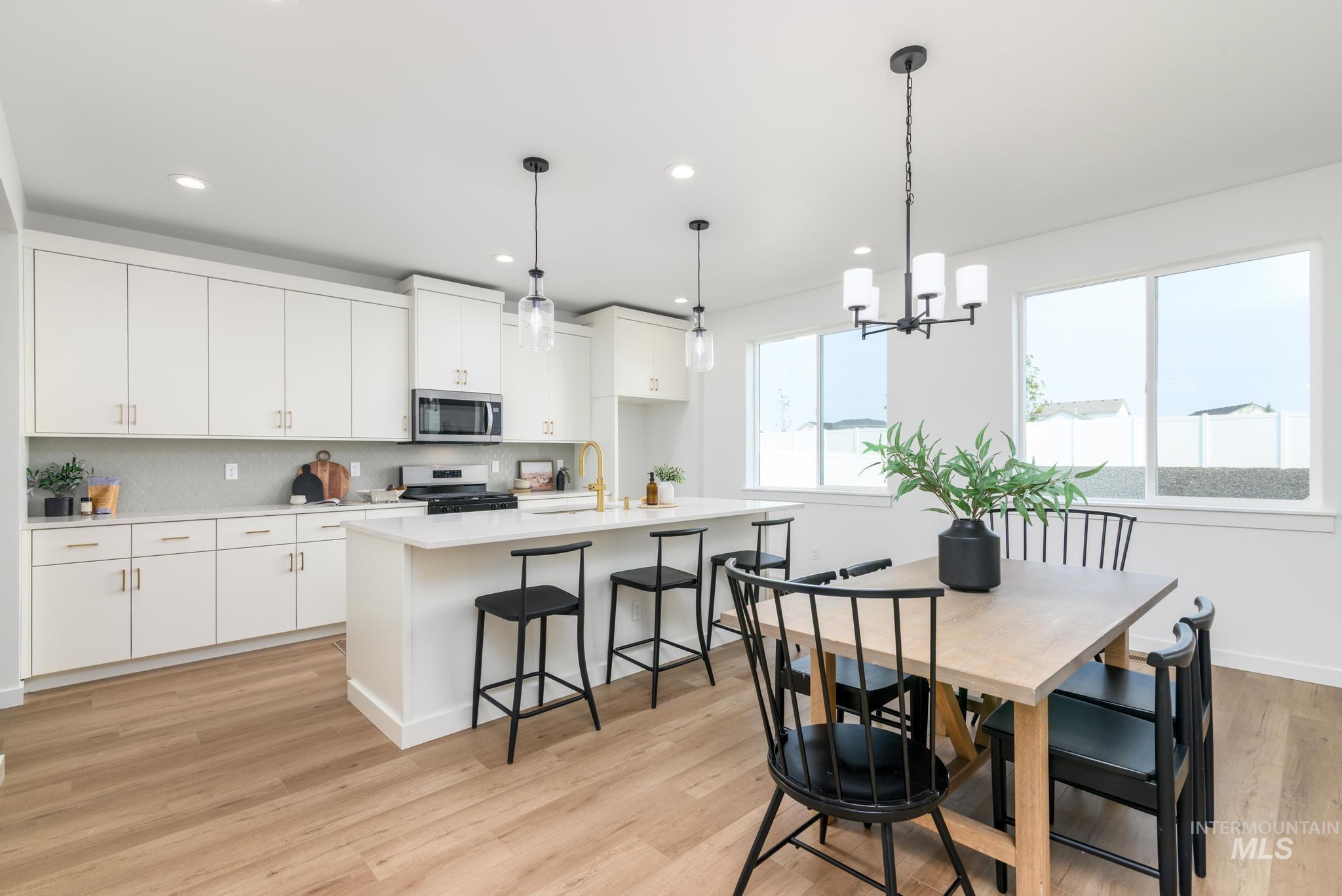 Kitchen with pendant lighting, backsplash, a kitchen bar, a kitchen island with sink, and recessed lighting