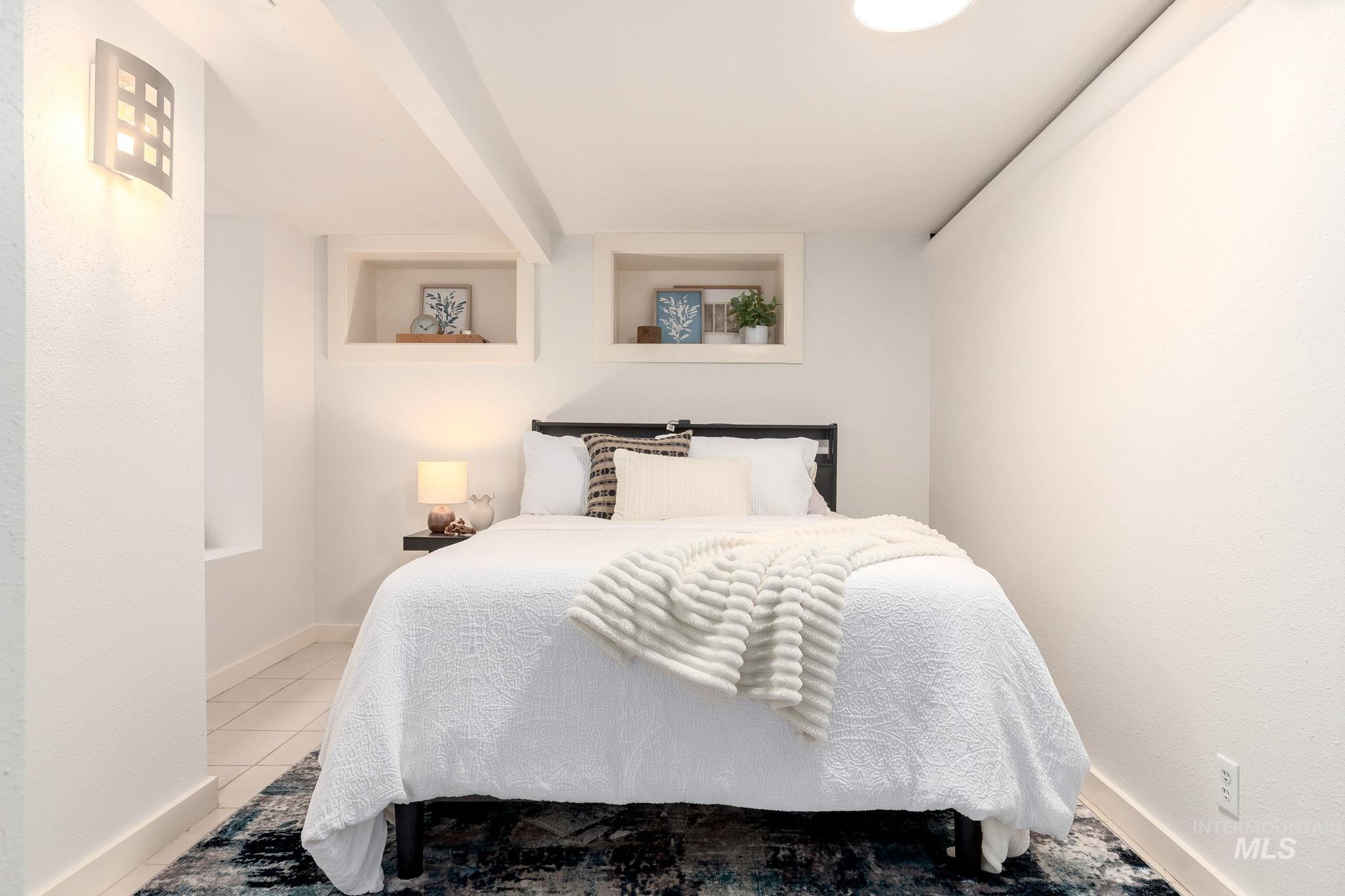 Bedroom with light tile patterned flooring and beam ceiling
