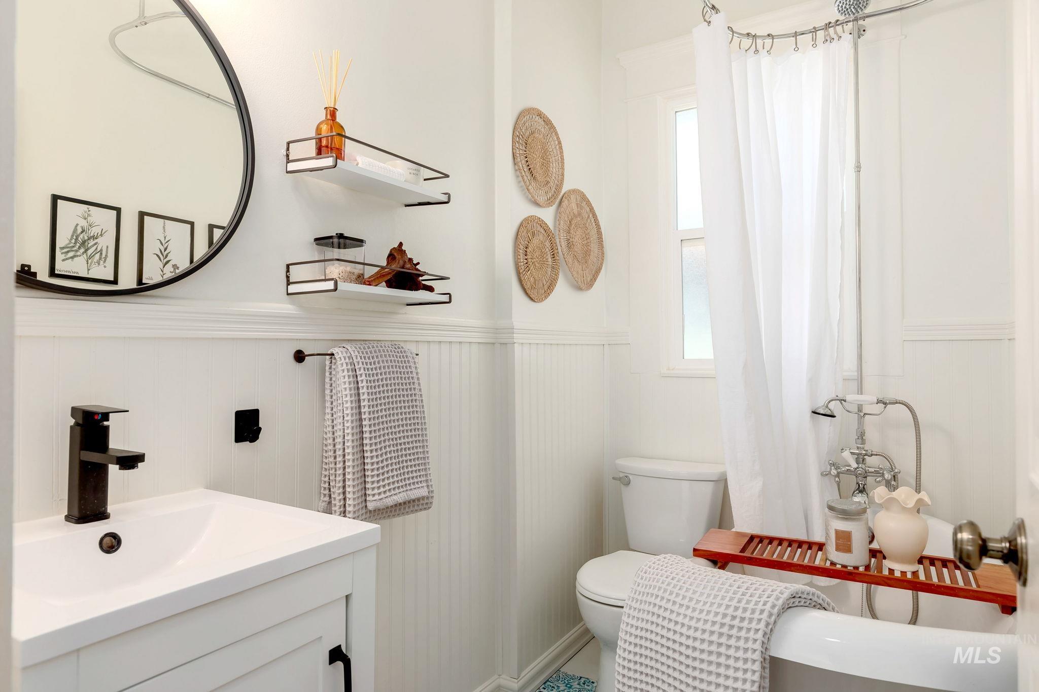 Full bathroom with vanity, a wainscoted wall, and a shower with curtain