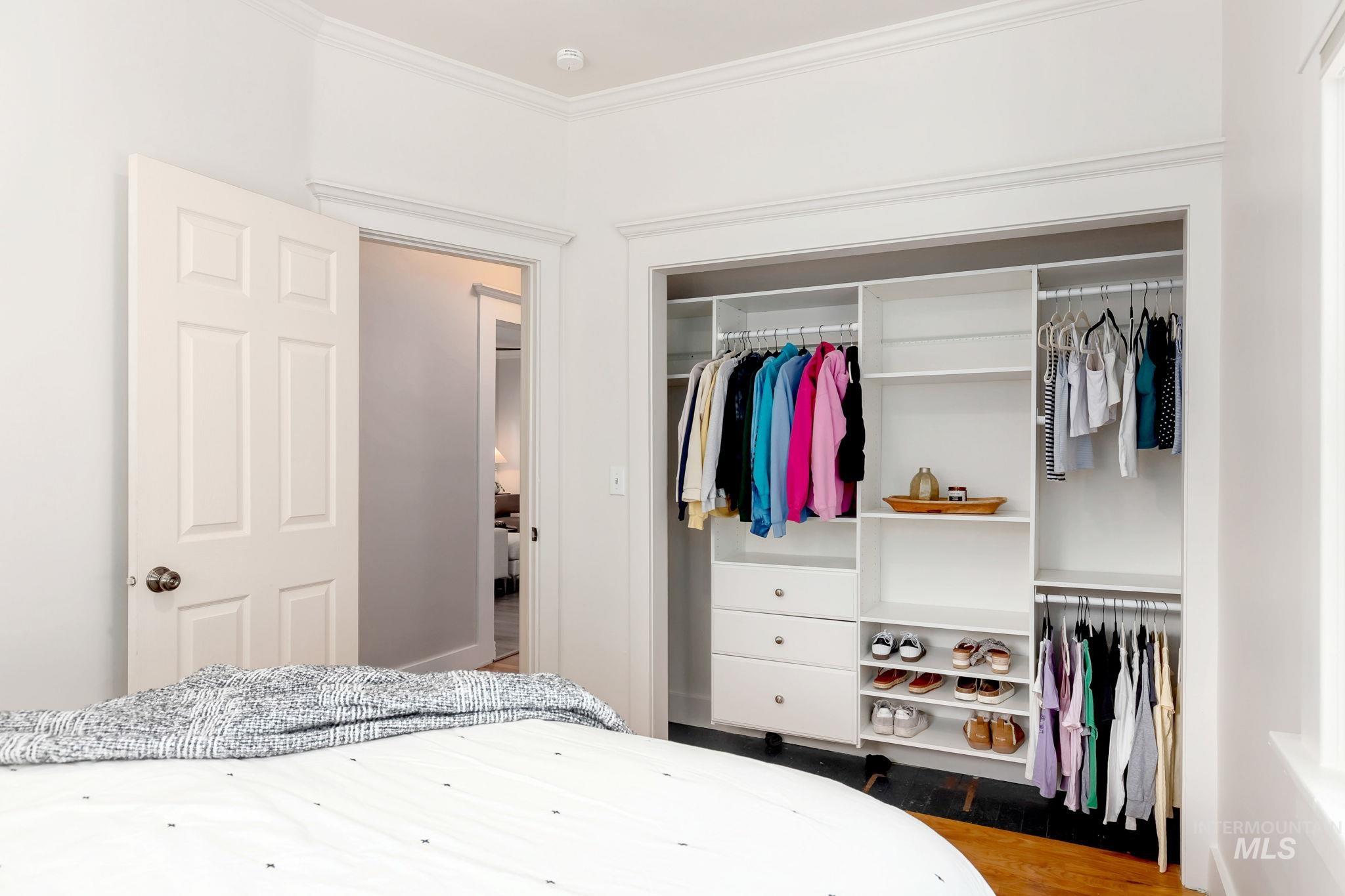 Bedroom featuring a closet, dark wood-style floors, and ornamental molding