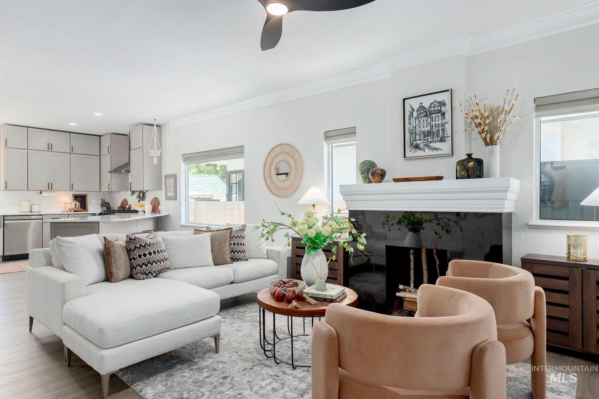 Living area featuring light wood-style floors, ornamental molding, a fireplace, and a ceiling fan