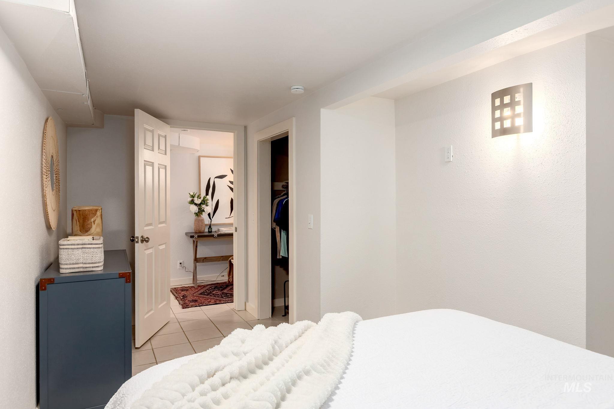 Bedroom with light tile patterned flooring and a walk in closet
