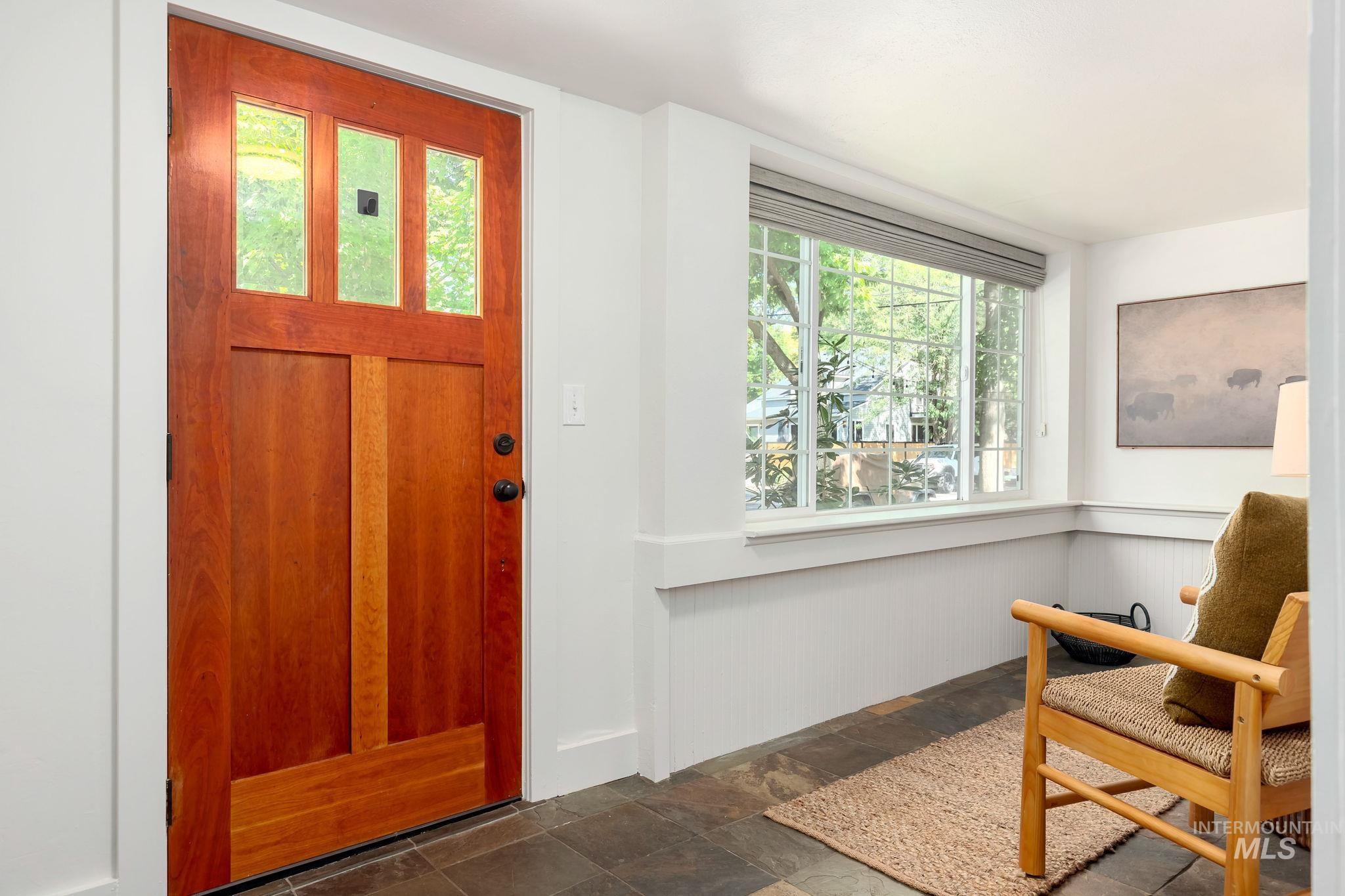 Foyer with dark stone finish floors and a wainscoted wall