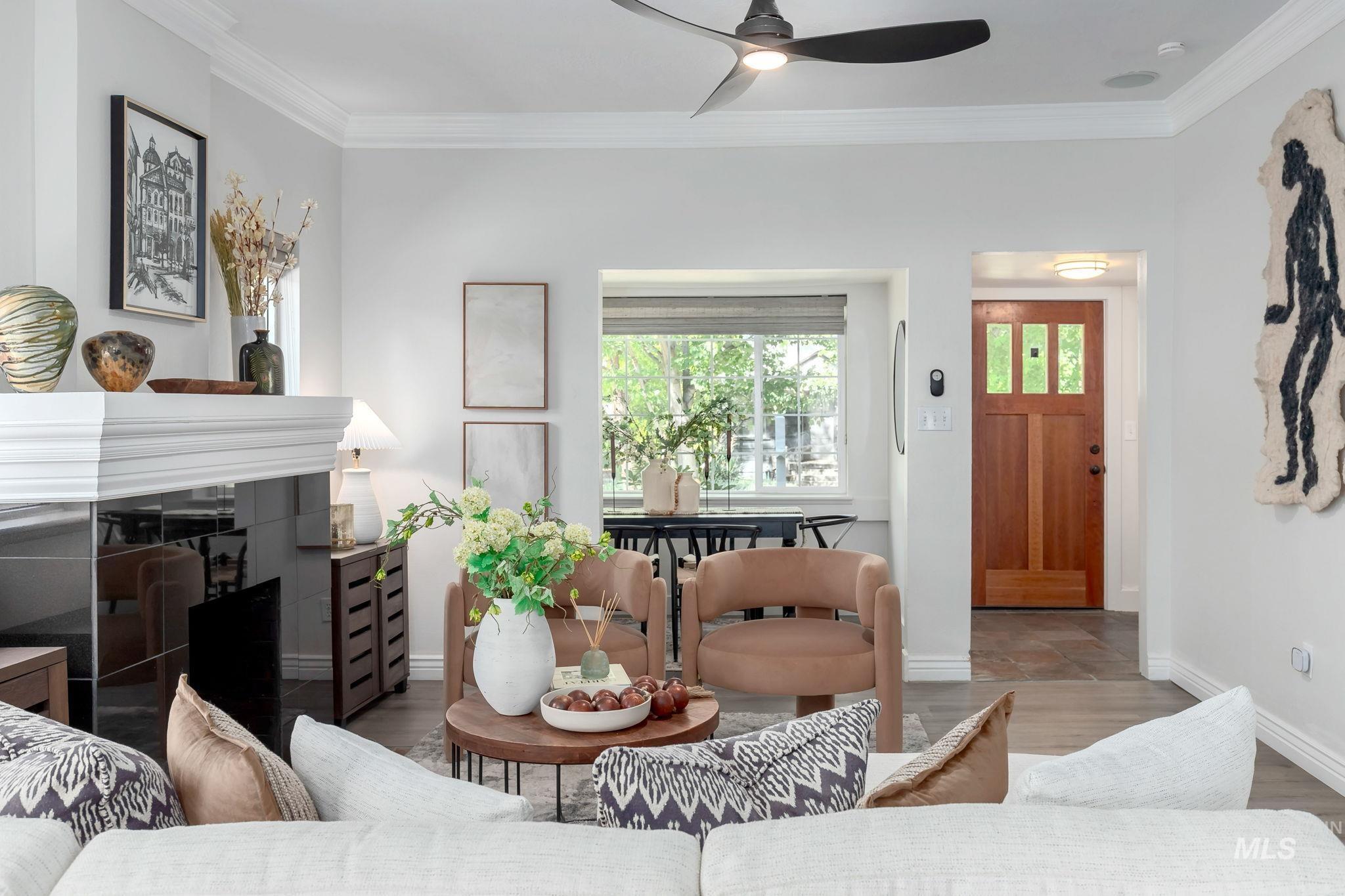 Living area featuring crown molding, wood finished floors, a fireplace, and ceiling fan