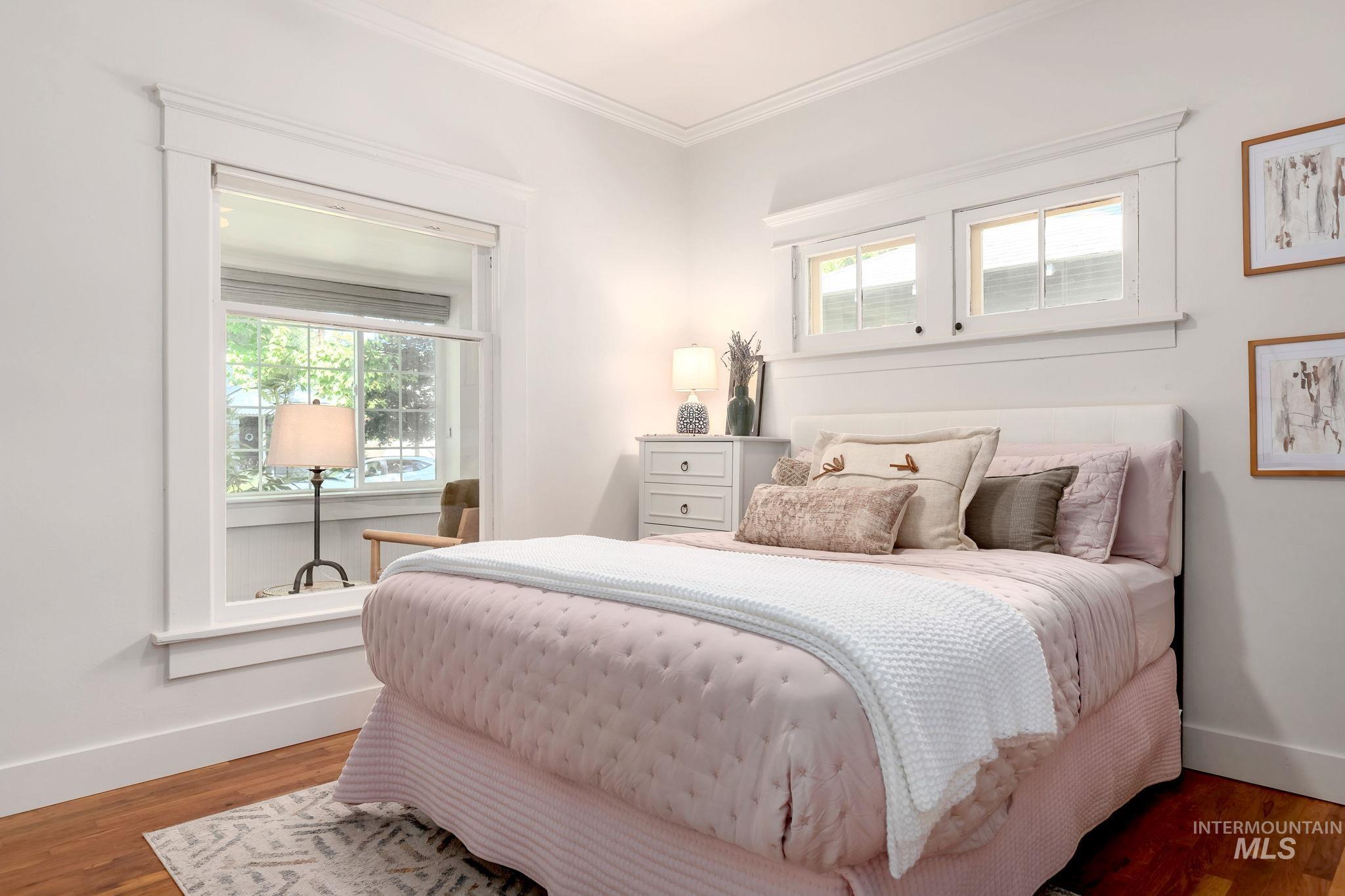 Bedroom featuring multiple windows, crown molding, and wood finished floors
