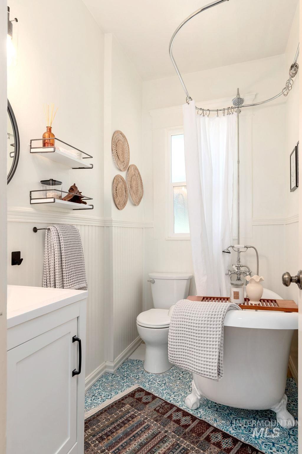 Full bath with vanity and a wainscoted wall