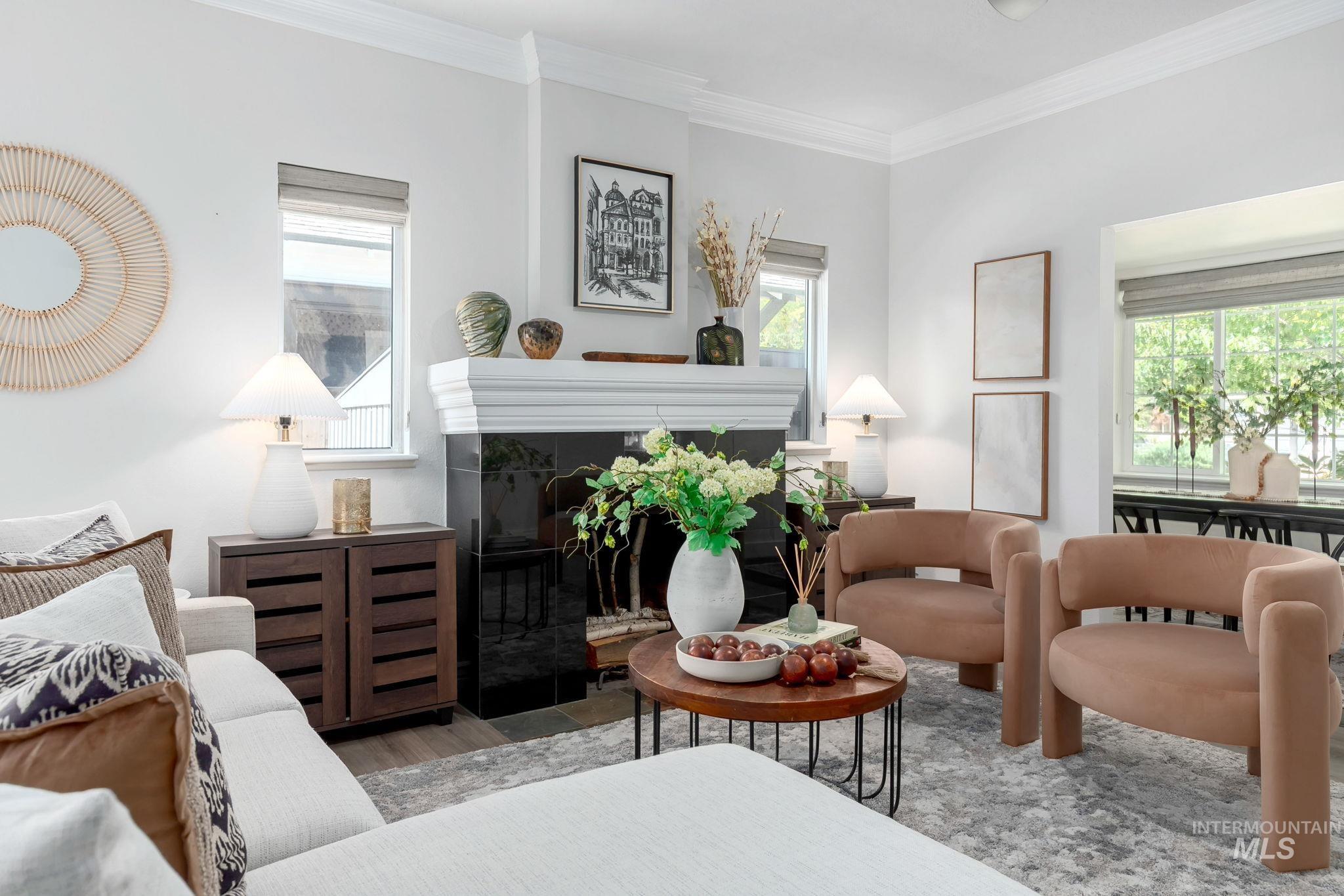 Living room with crown molding, a glass covered fireplace, healthy amount of natural light, and wood finished floors