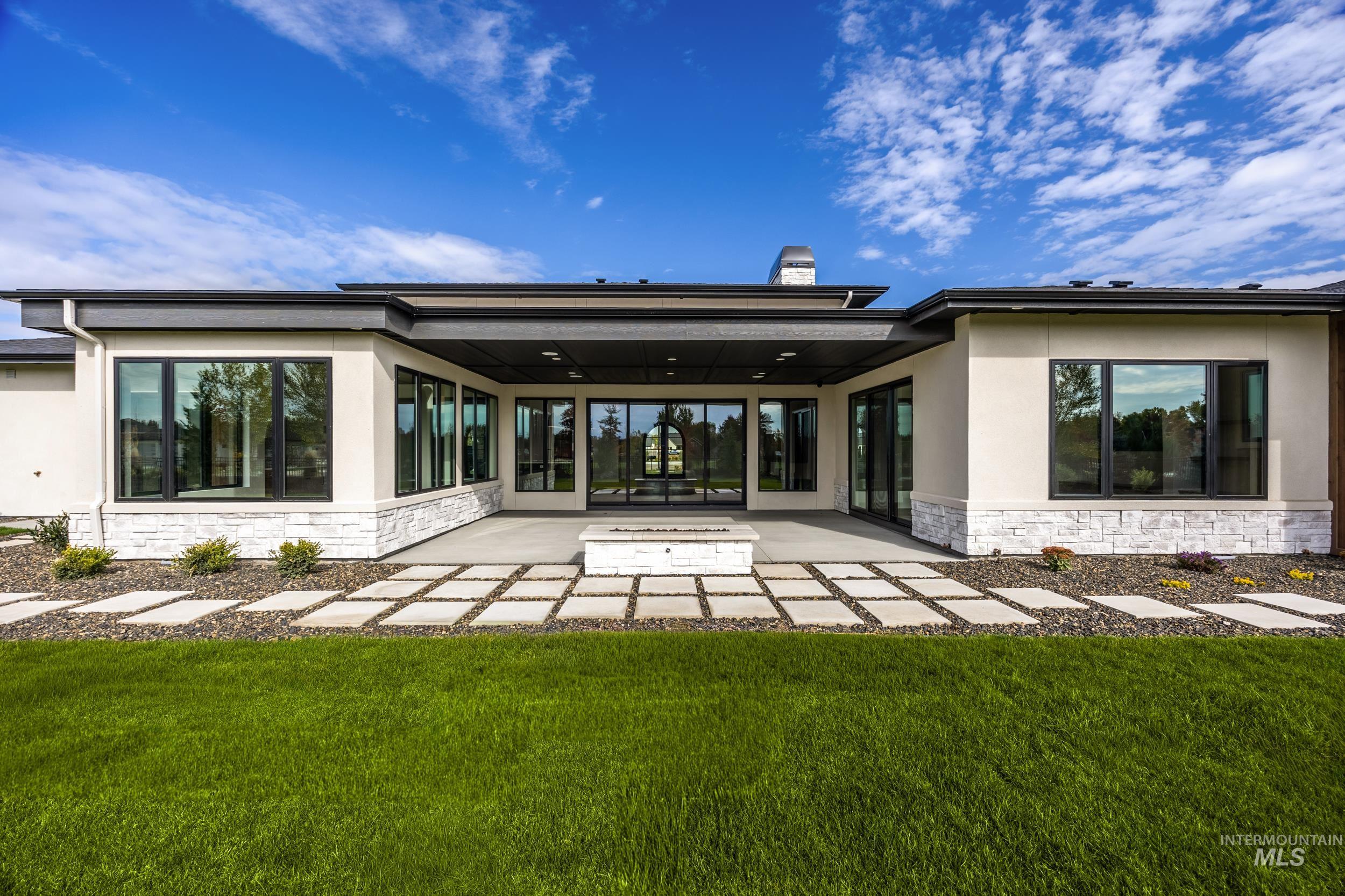 Rear view of property with stone siding, stucco siding, and a lawn
