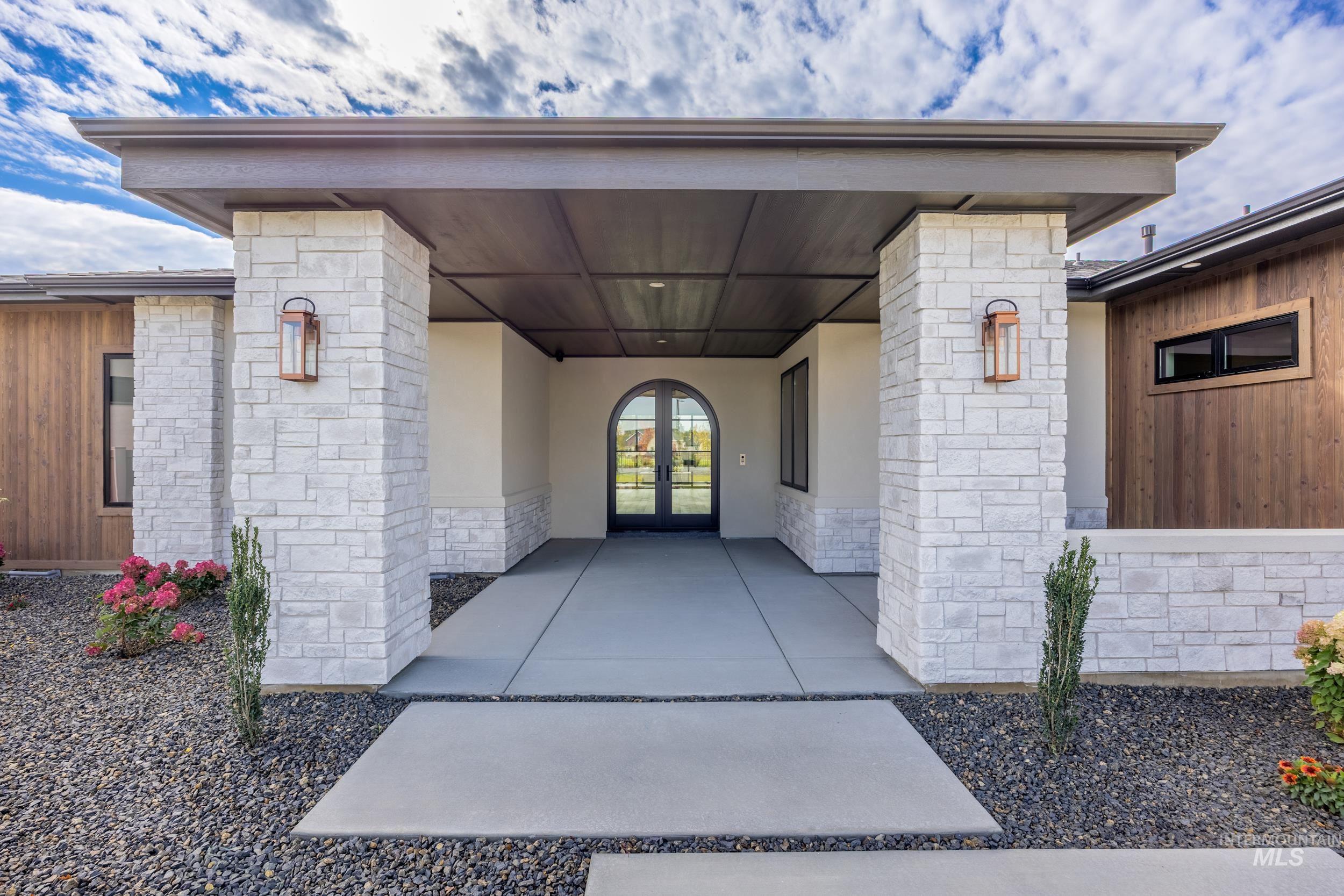 Entrance to property featuring stone siding, french doors, and stucco siding