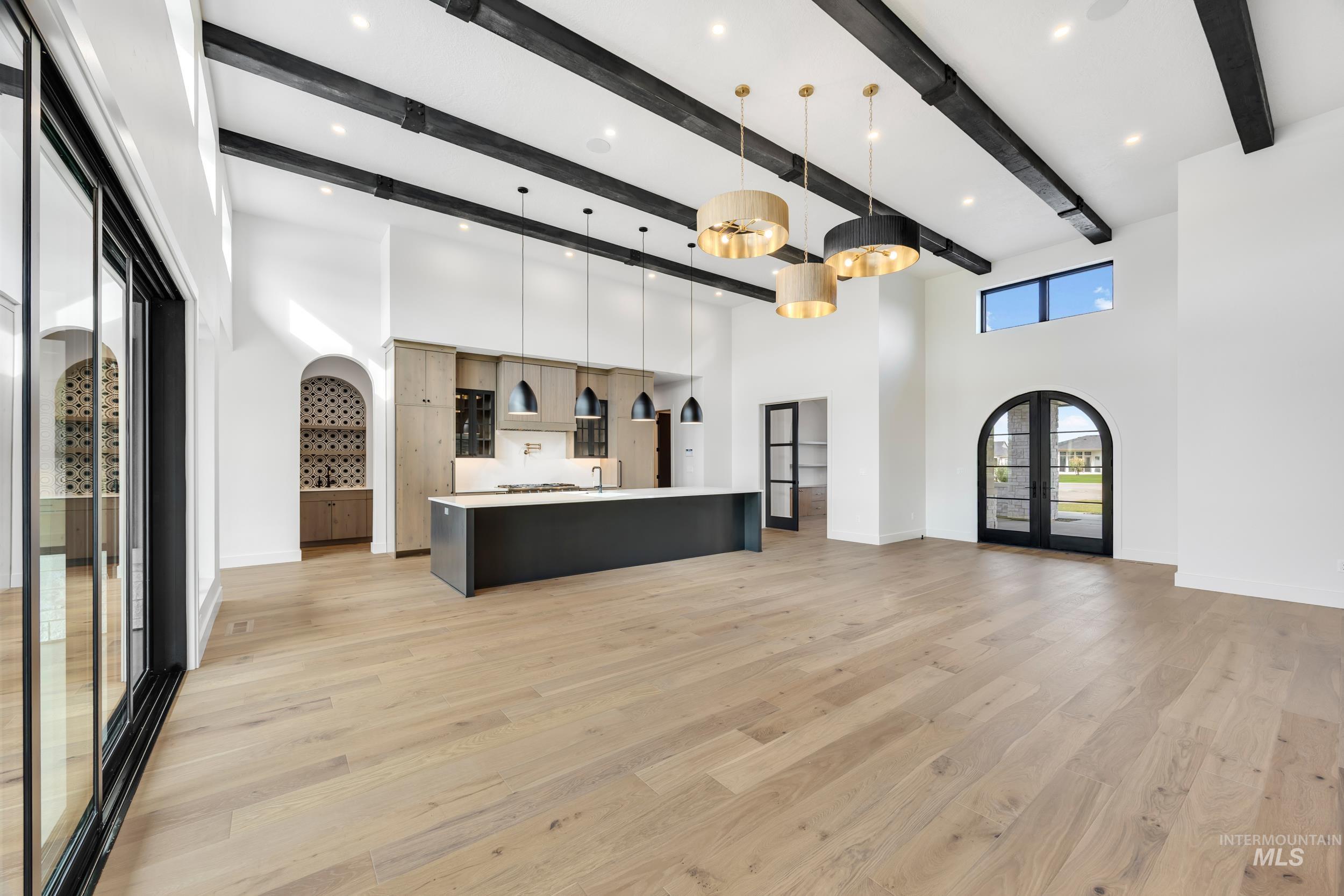 Kitchen featuring pendant lighting, arched walkways, french doors, open floor plan, and light wood finished floors
