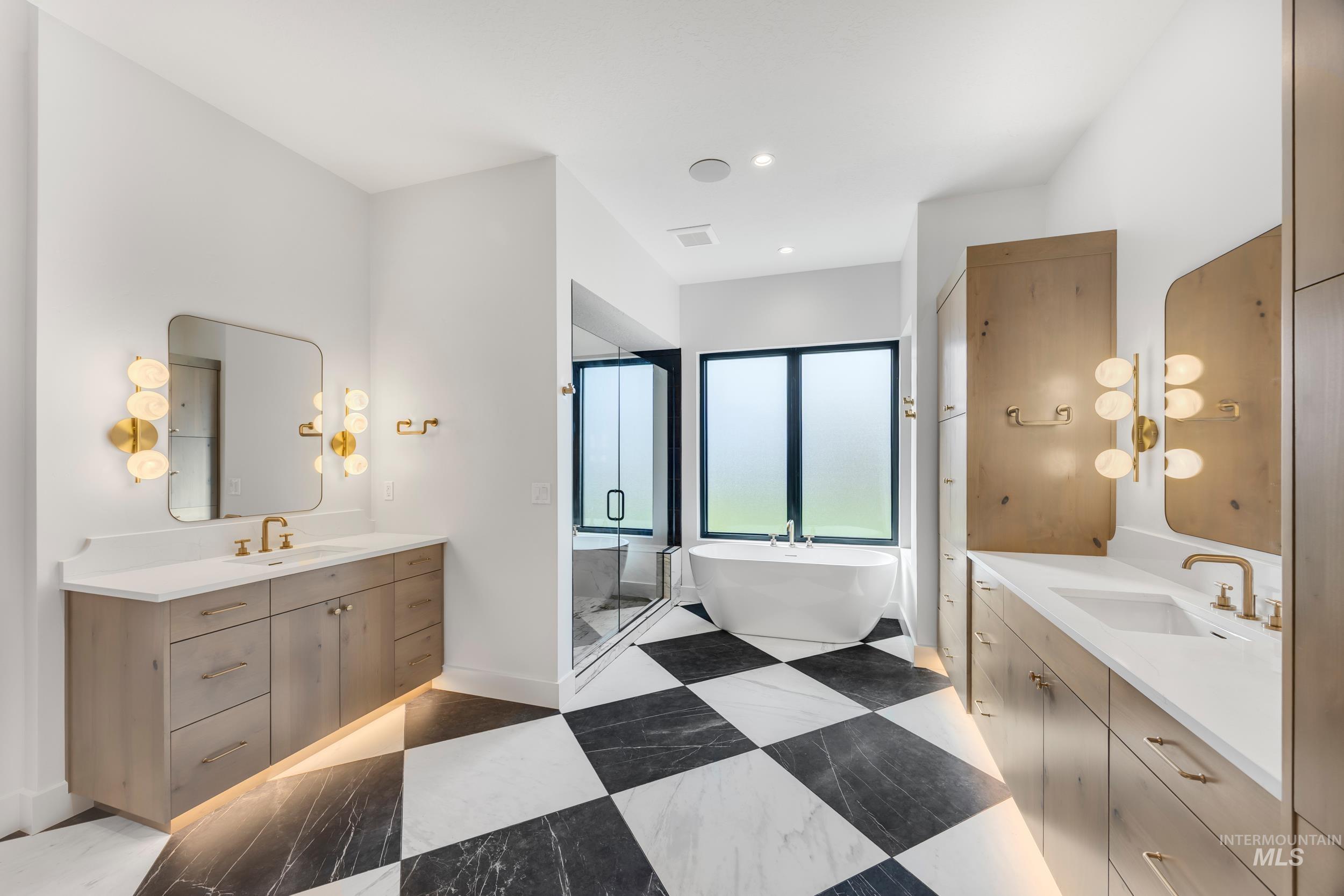 Full bathroom featuring two vanities, a soaking tub, a shower stall, and recessed lighting