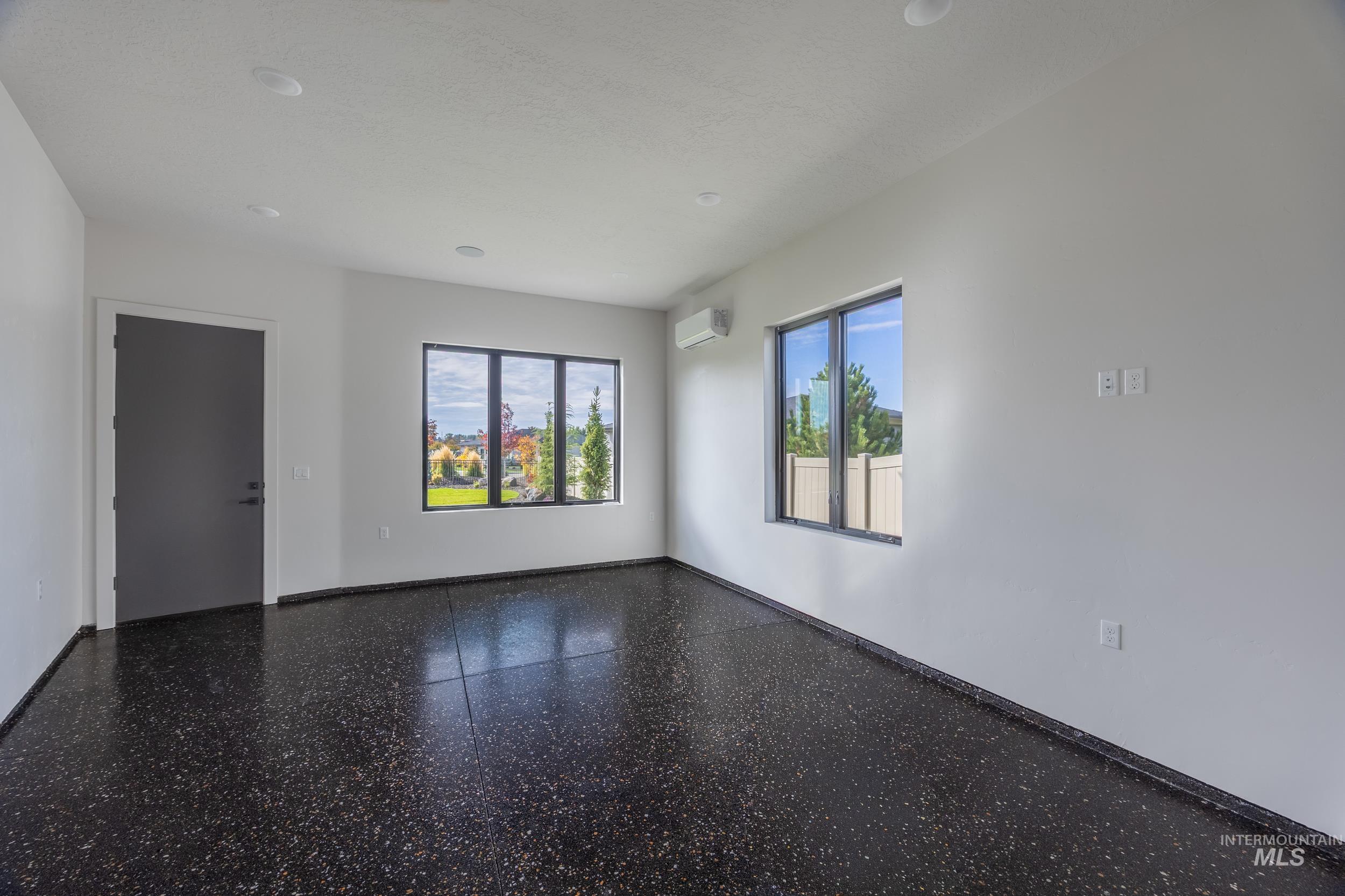 Unfurnished room with speckle patterned floor, recessed lighting, and a wall mounted AC
