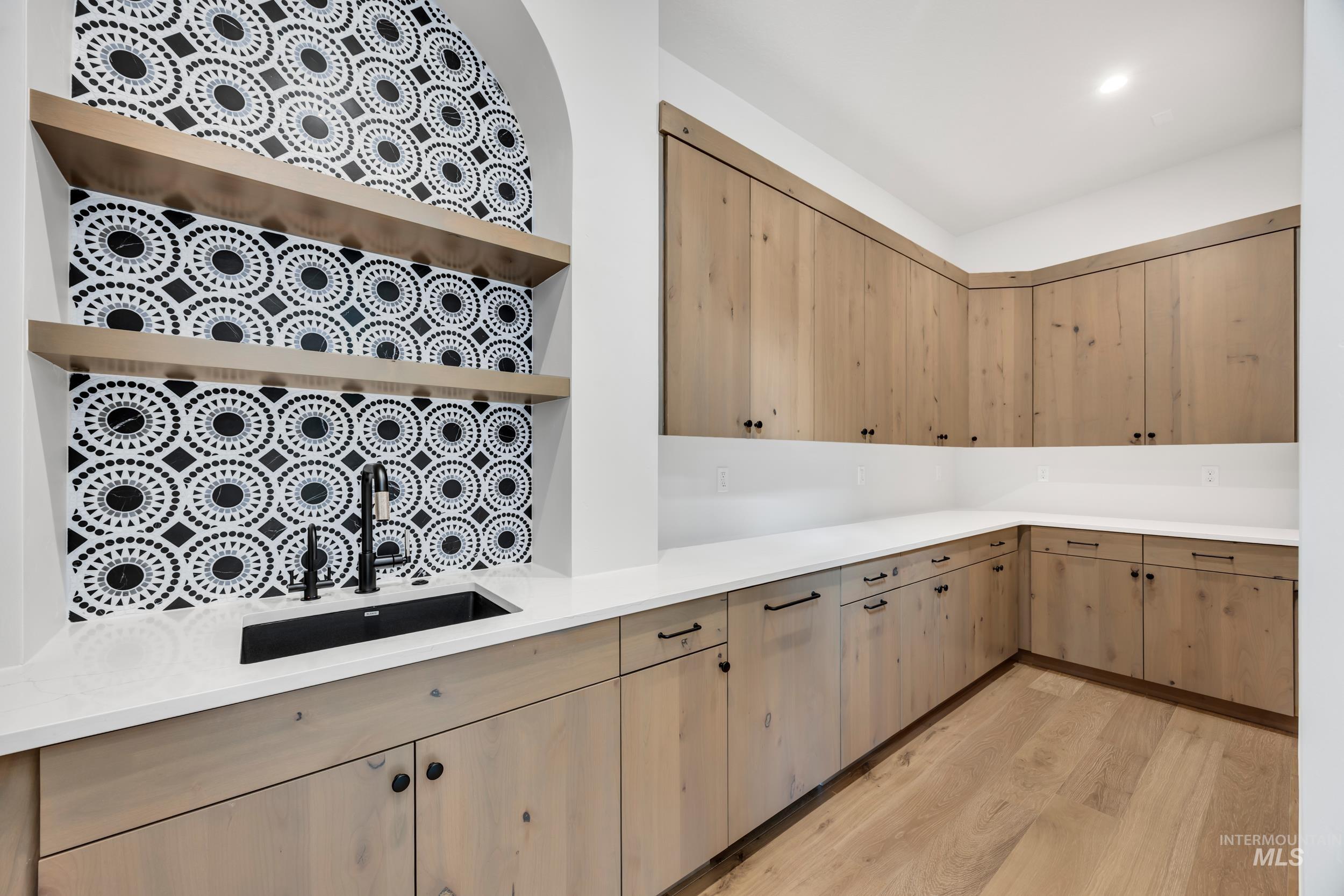 Kitchen featuring open shelves, light brown cabinetry, light wood-style flooring, light stone countertops, and modern cabinets