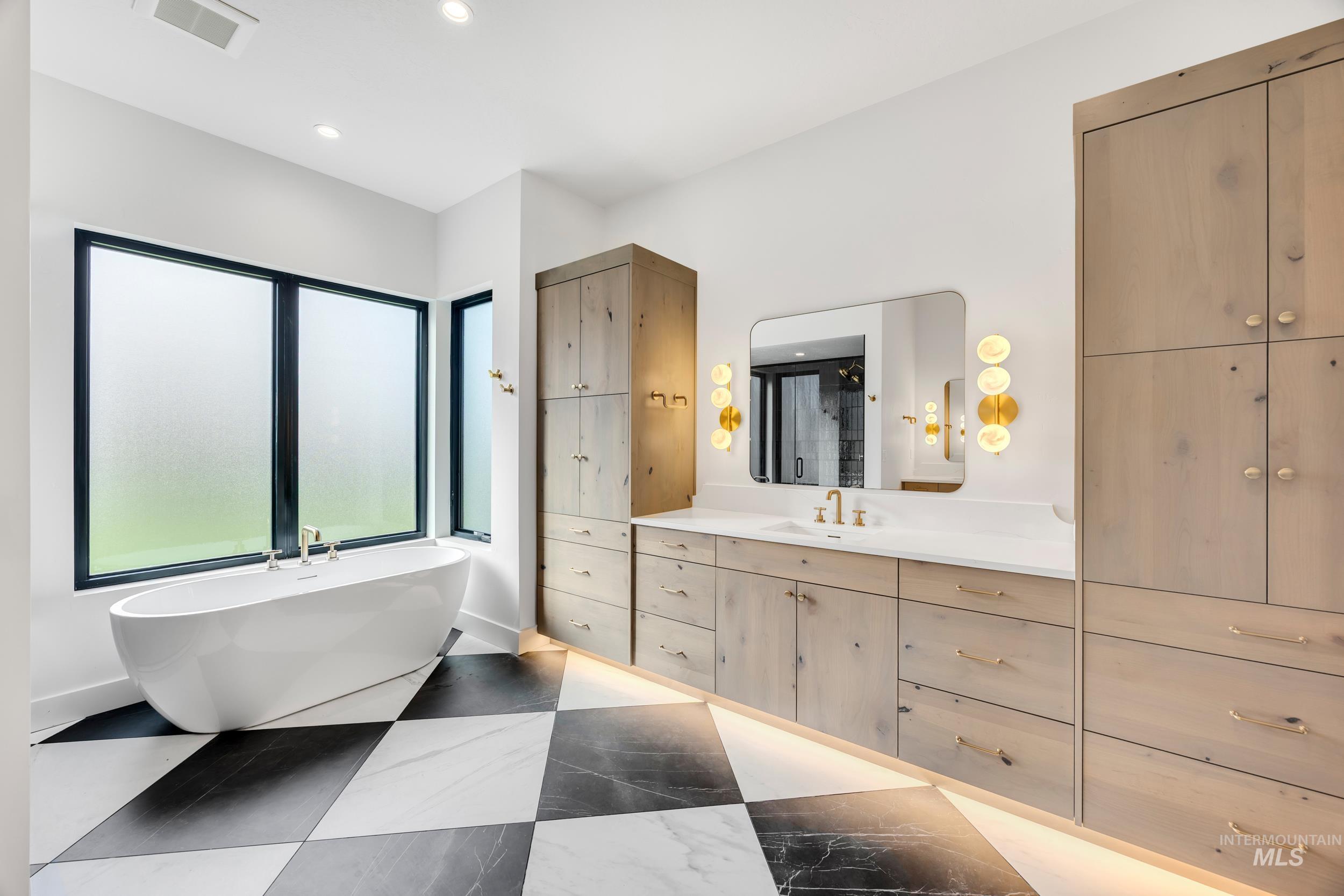 Full bathroom featuring a freestanding bath, vanity, and recessed lighting