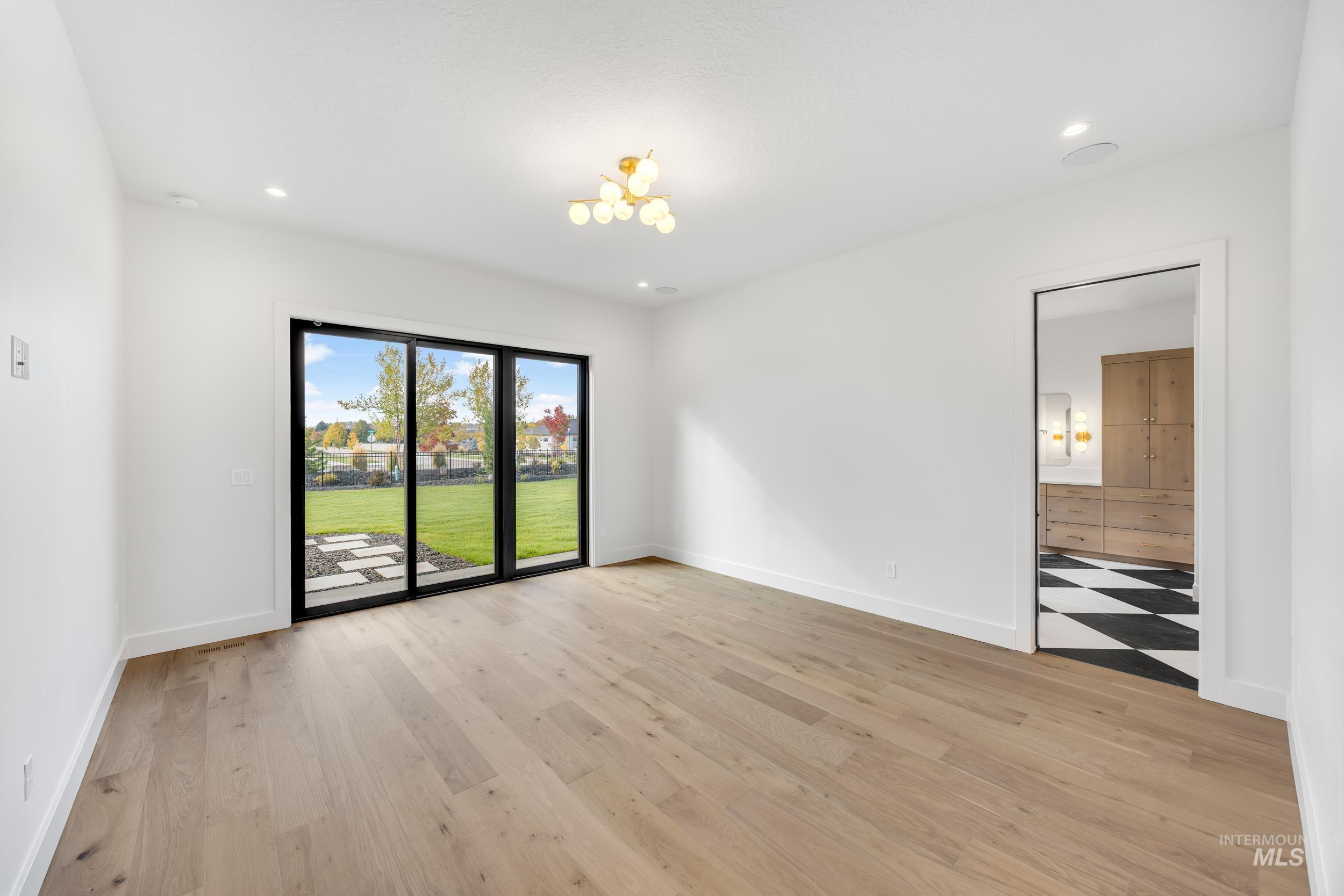 Empty room featuring light wood-type flooring, recessed lighting, and a chandelier