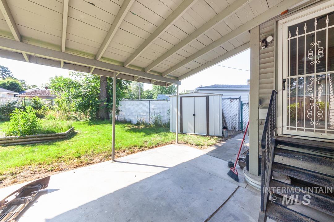 Fenced backyard featuring a patio, a storage unit, and entry steps