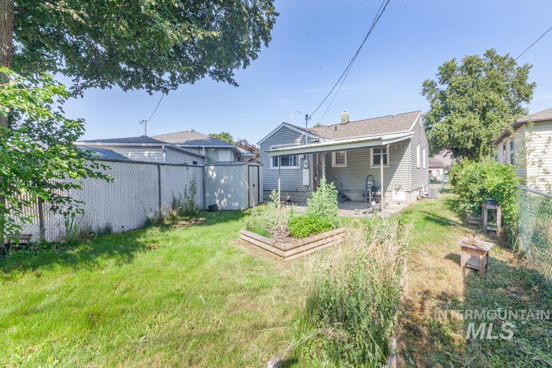 Back of property featuring a fenced backyard, a garden, a storage shed, and a patio