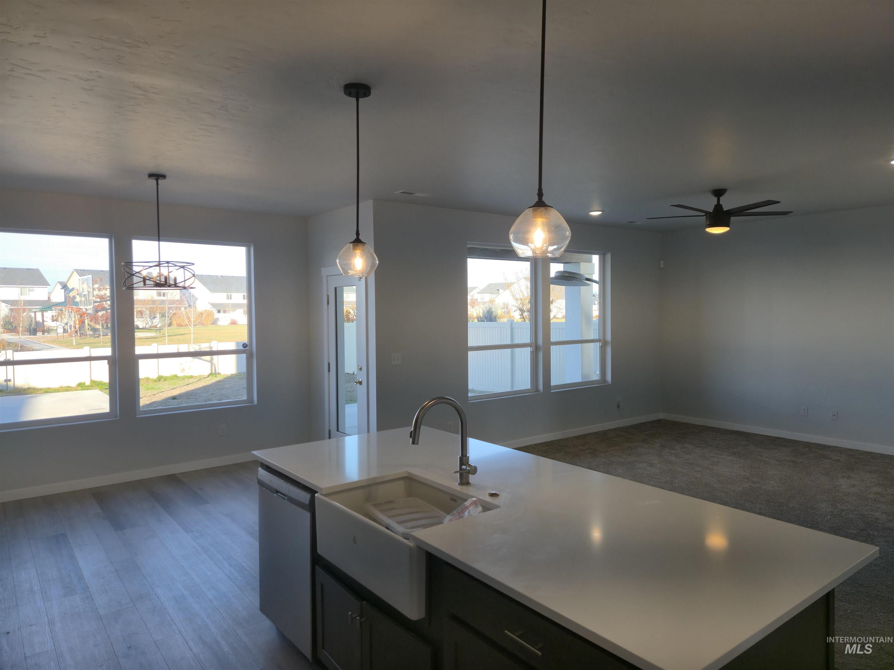 Kitchen featuring a center island with sink, open floor plan, pendant lighting, stainless steel dishwasher, and a ceiling fan
