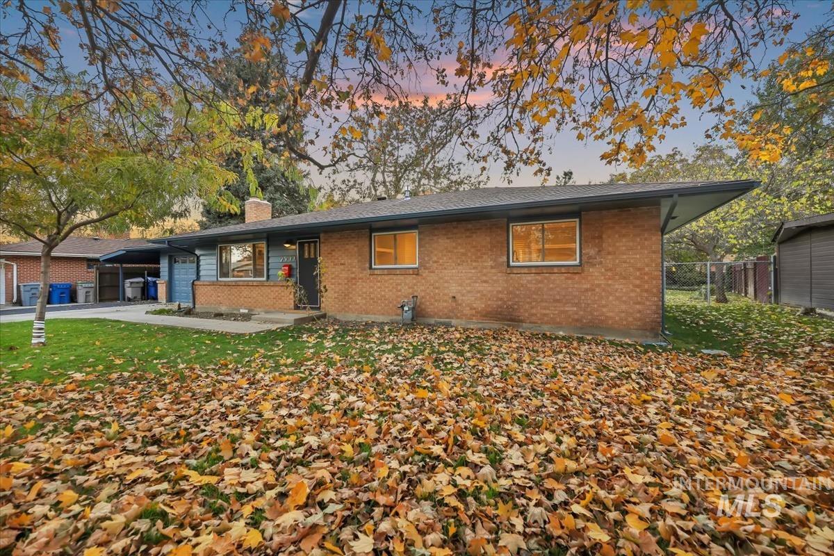 View of front of home featuring brick siding, a chimney, and concrete driveway
