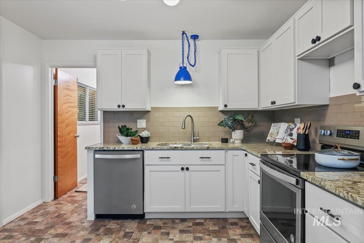 Kitchen featuring stainless steel appliances, white cabinets, stone finish floors, and light stone counters