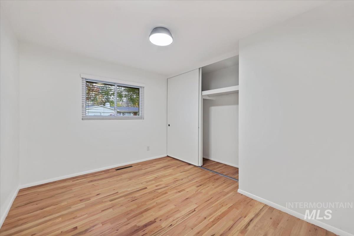 Unfurnished bedroom featuring light wood finished floors and a closet