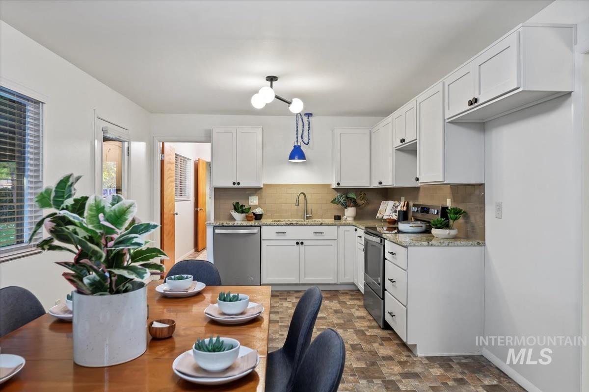 Kitchen with backsplash, white cabinets, light stone countertops, stainless steel appliances, and stone finish flooring