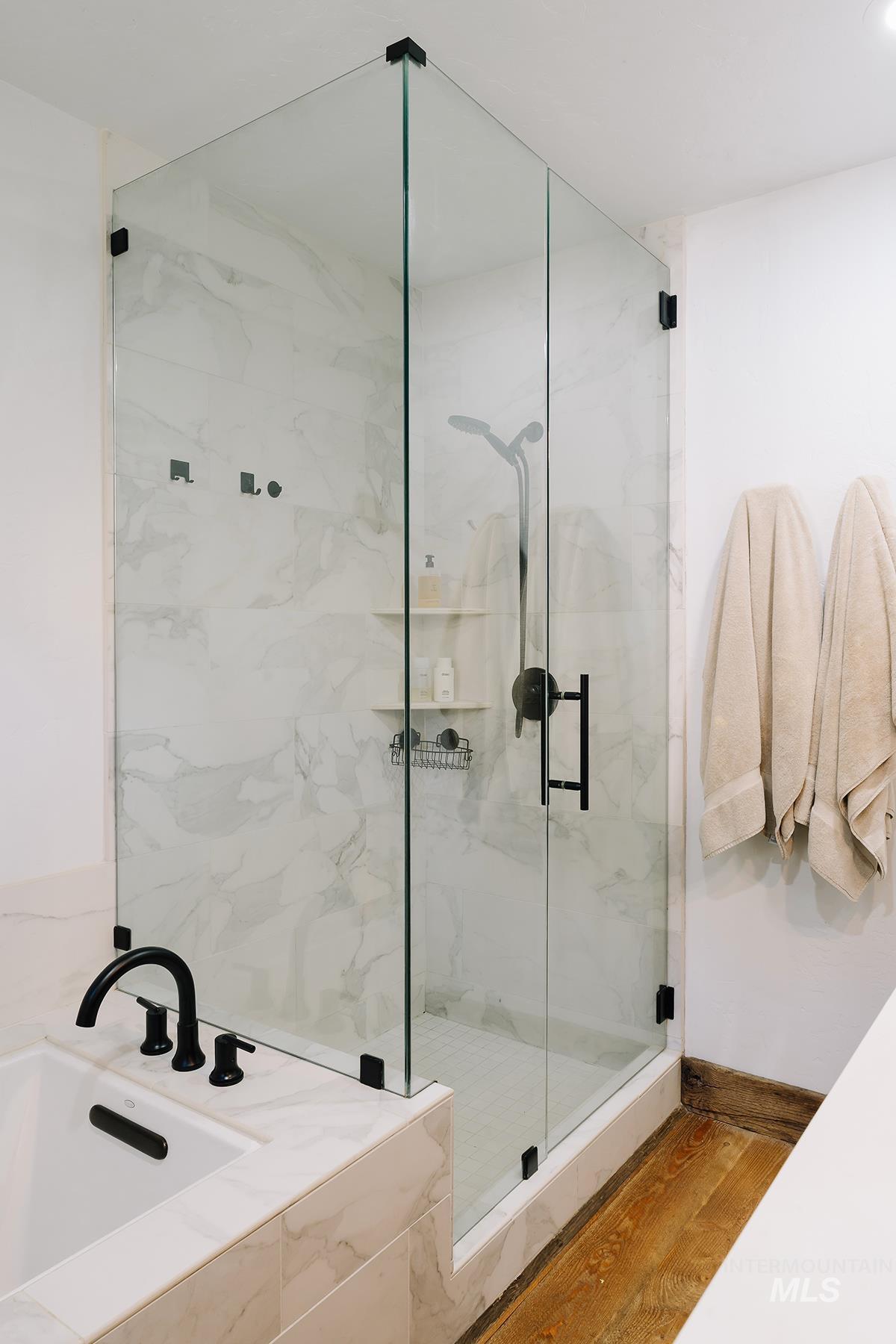 Full bathroom with wood finished floors, a garden tub, and a marble finish shower
