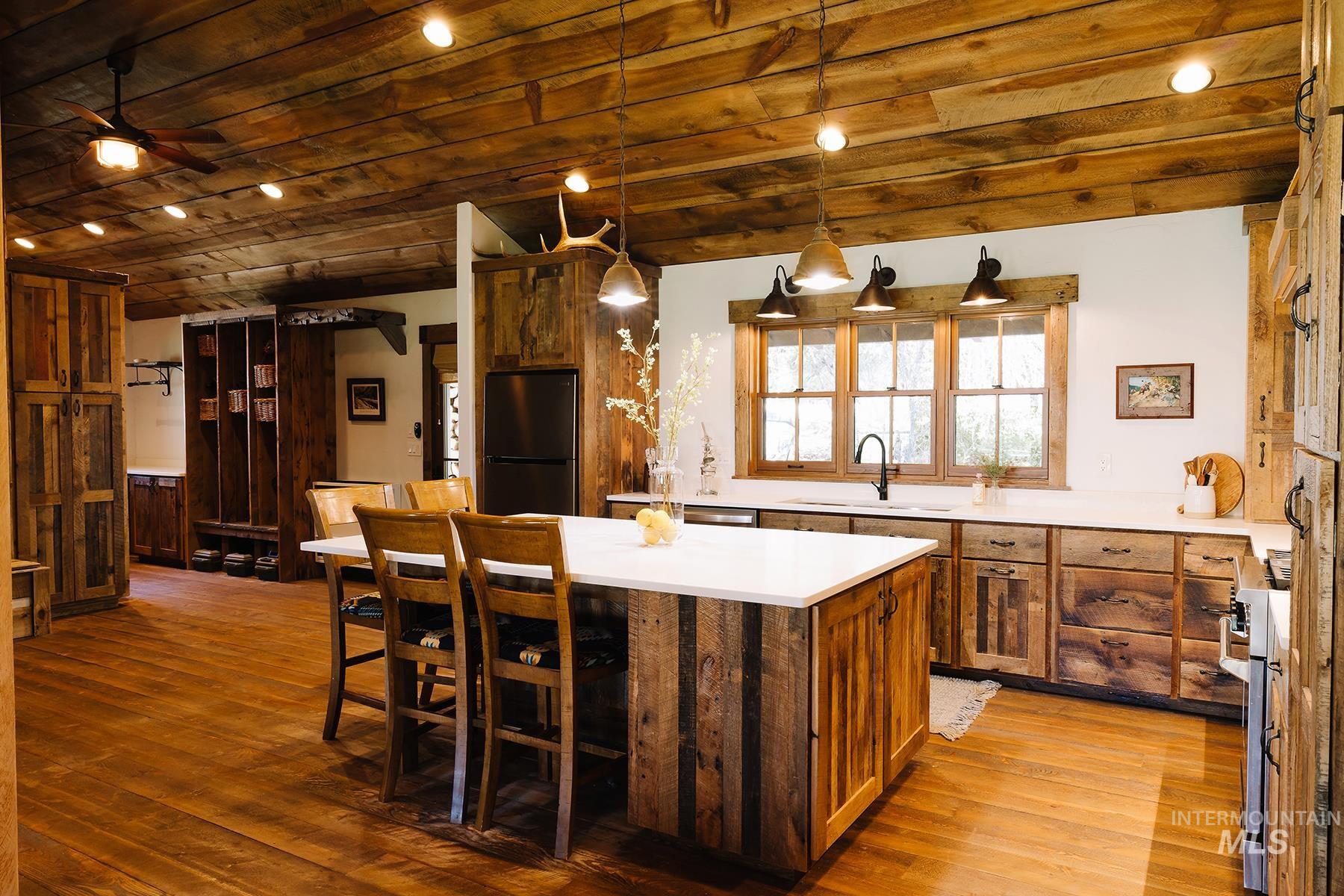 Kitchen featuring pendant lighting, freestanding refrigerator, light wood-style floors, a kitchen island, and wood ceiling