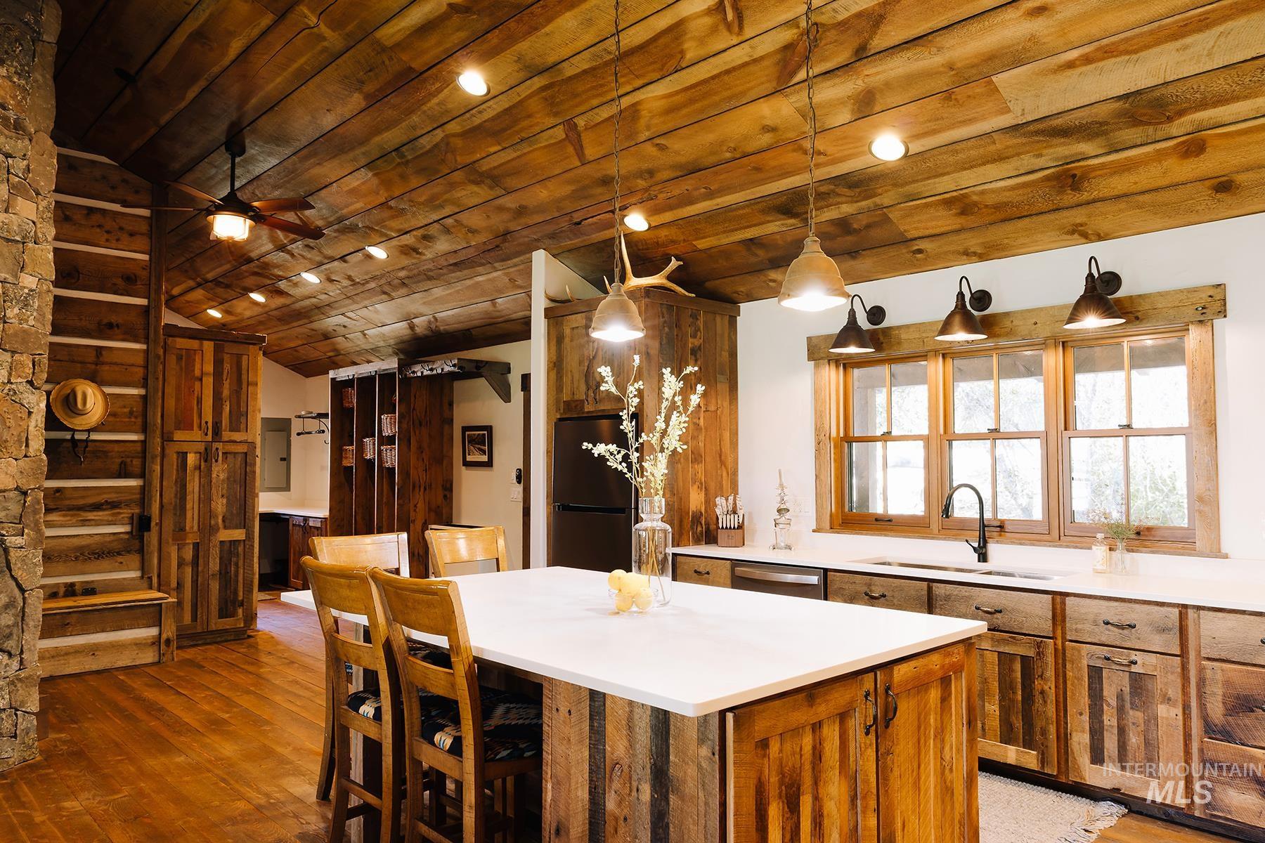 Kitchen with hanging light fixtures, brown cabinets, freestanding refrigerator, a center island, and wood ceiling