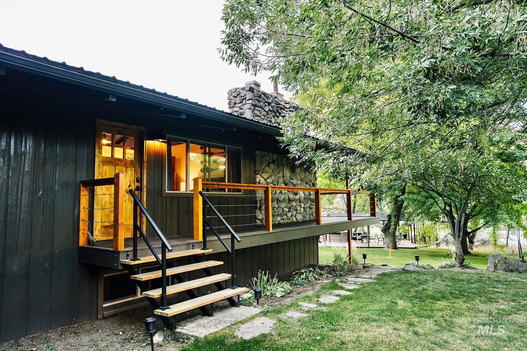 View of exterior entry featuring a wooden deck, a chimney, and a lawn