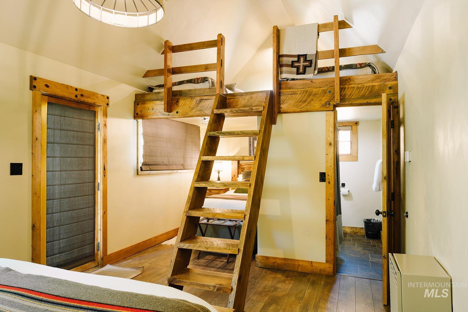 Bedroom with hardwood / wood-style flooring and lofted ceiling