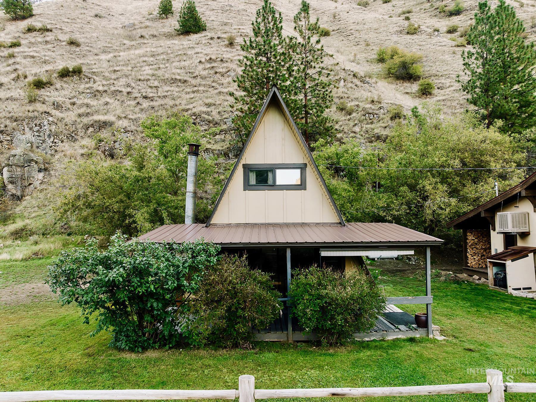 View of front facade with a front lawn, a wall unit AC, and a metal roof